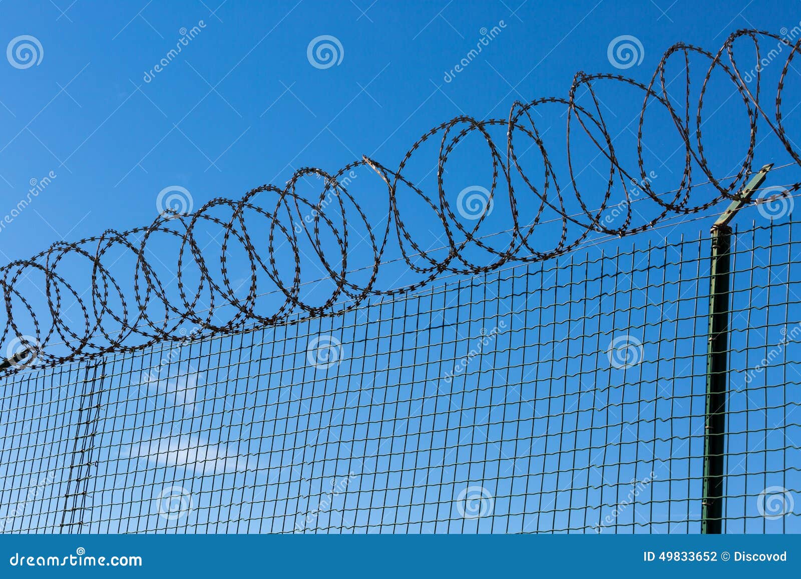 Wired Fence with Spiral Barbwire on Blue Sky Background