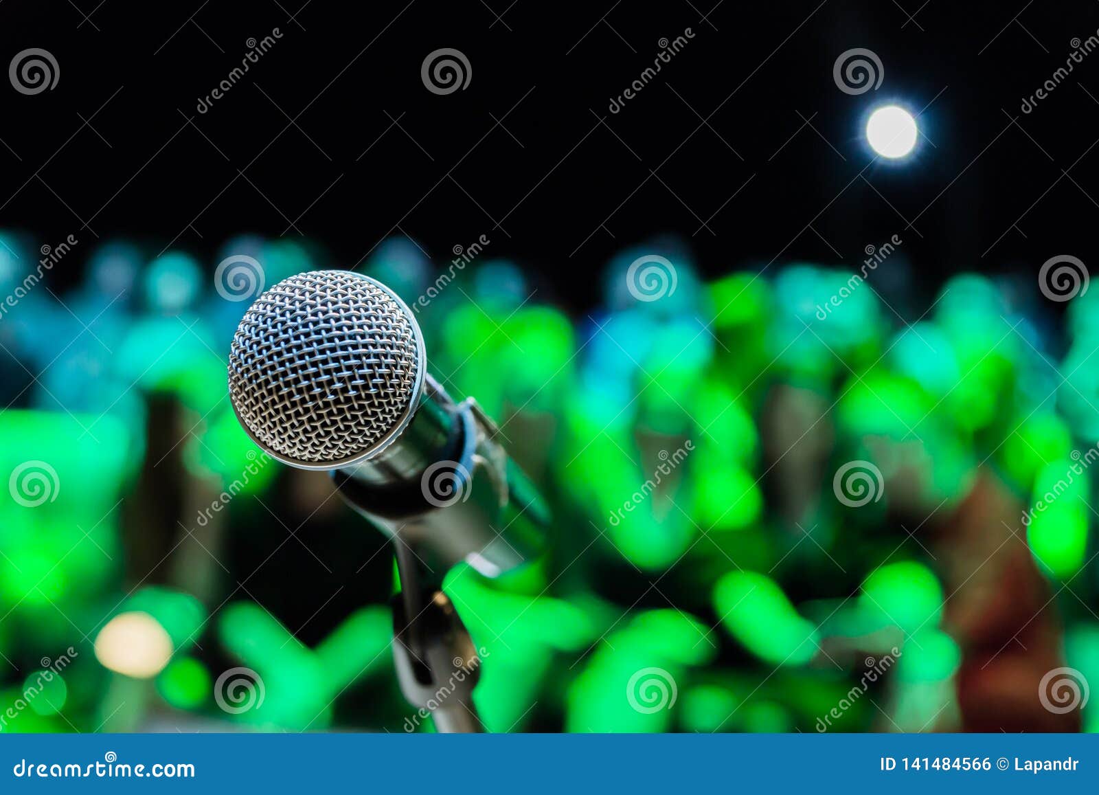 wireless microphone on the stand. blurred background. people in the audience. show on stage in the theater or concert hall