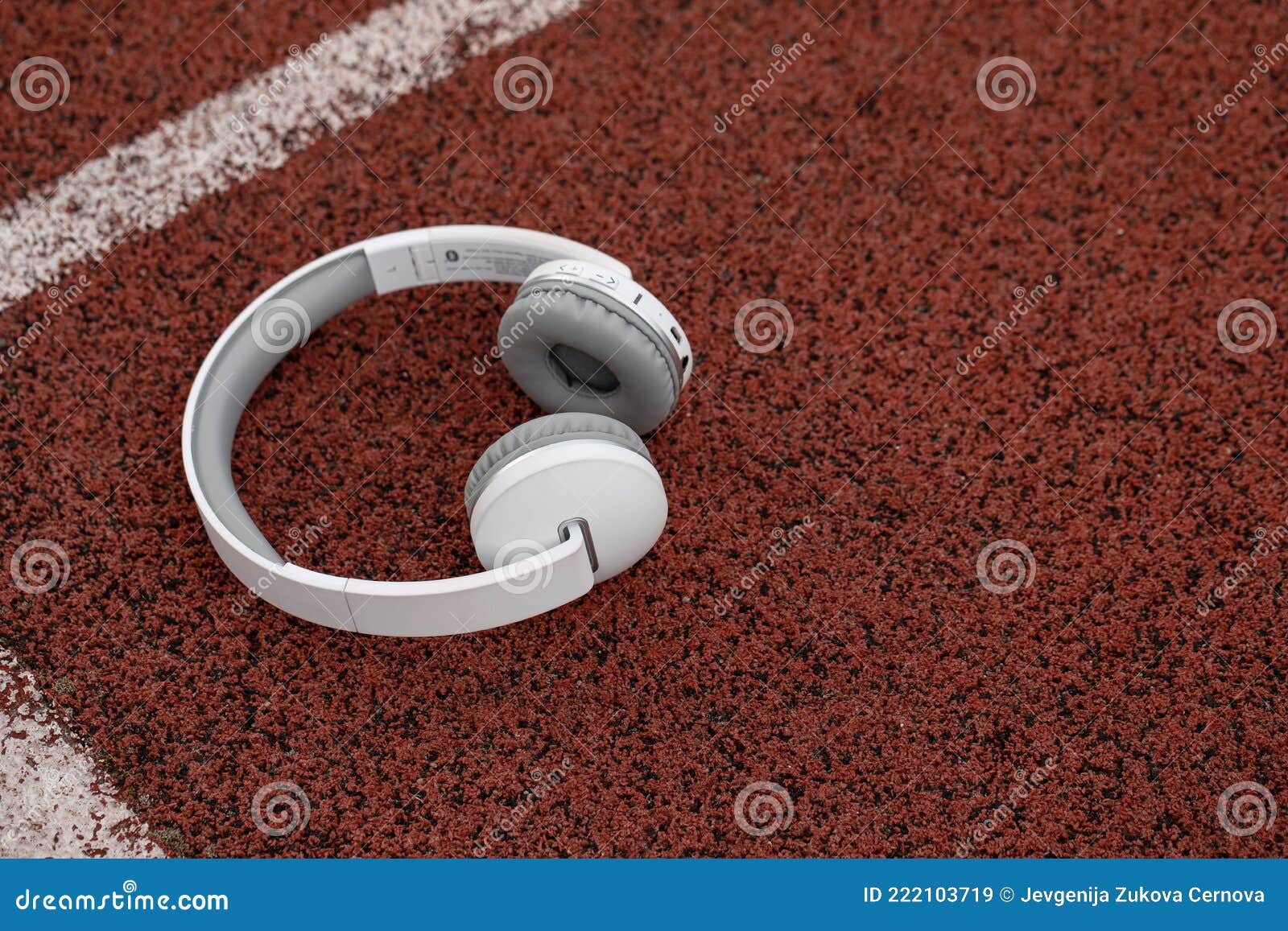 Wireless White Headphones on Red Racing Track Rubber Background. Stock