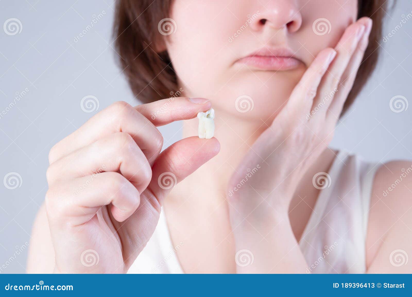 wisdom tooth extraction, woman suffering from a toothache on gray background