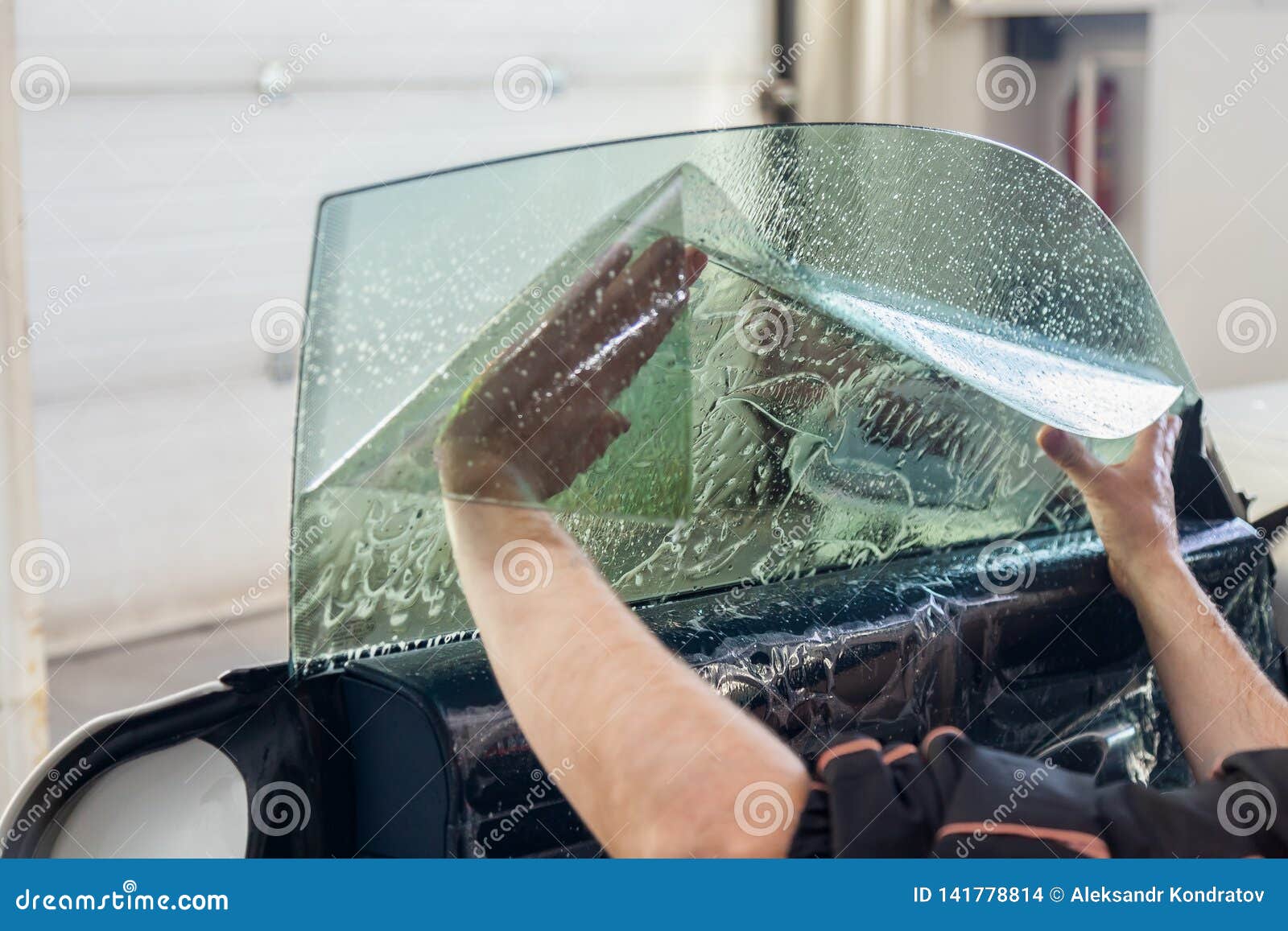 the wizard for installing additional equipment sticks a tint film on the side front glass of the car and flattens it by hand to