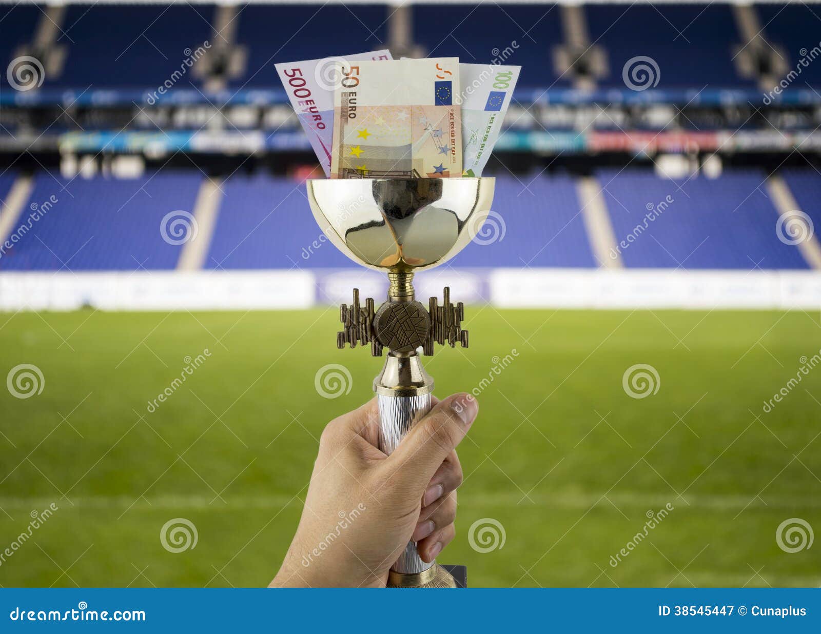 Więcej euro więcej tytuły z tłem stadium. Ręka podnosi trofeum z euro w więcej pieniądze pojęciu z więcej tytułami funduje stadium