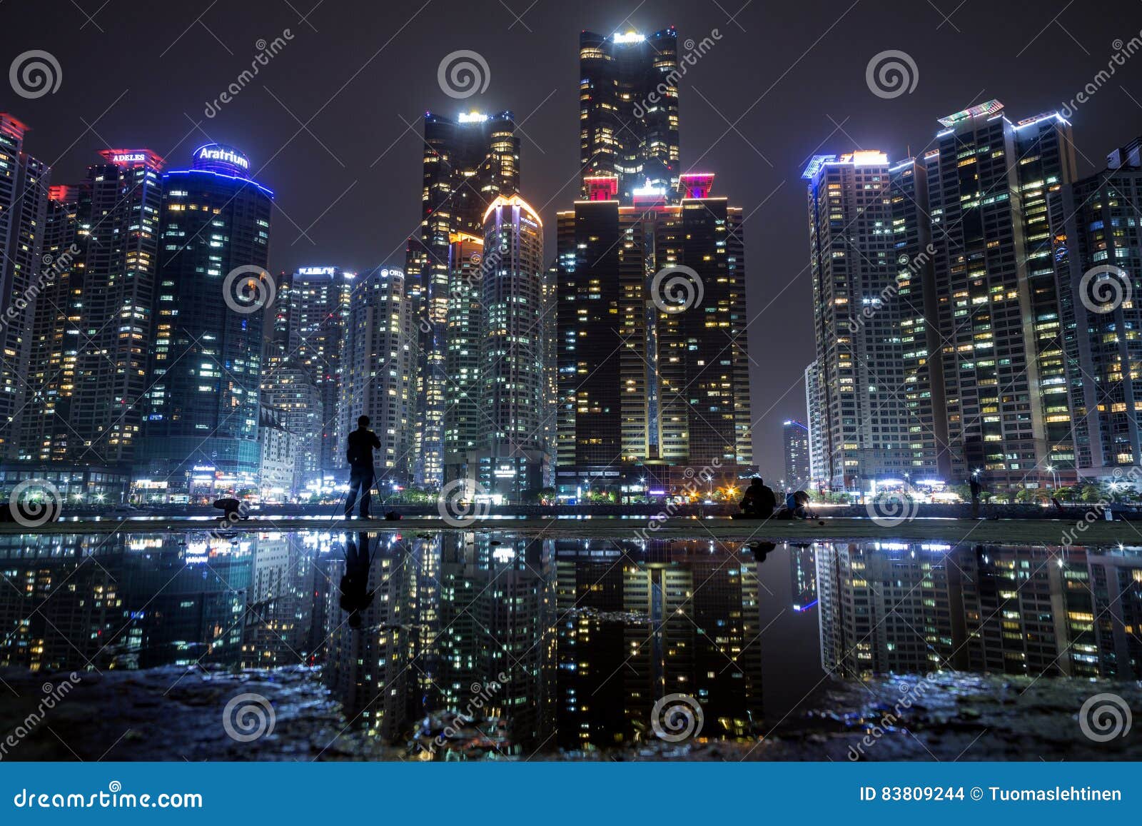 Wolkenkratzer bei Marine City in Busan nachts. Ansicht von Wolkenkratzern am Marine City-Wohngebiet in Haeundae-Bezirk und an ihrer Reflexion in einer Pfütze in Busan, Südkorea, nachts