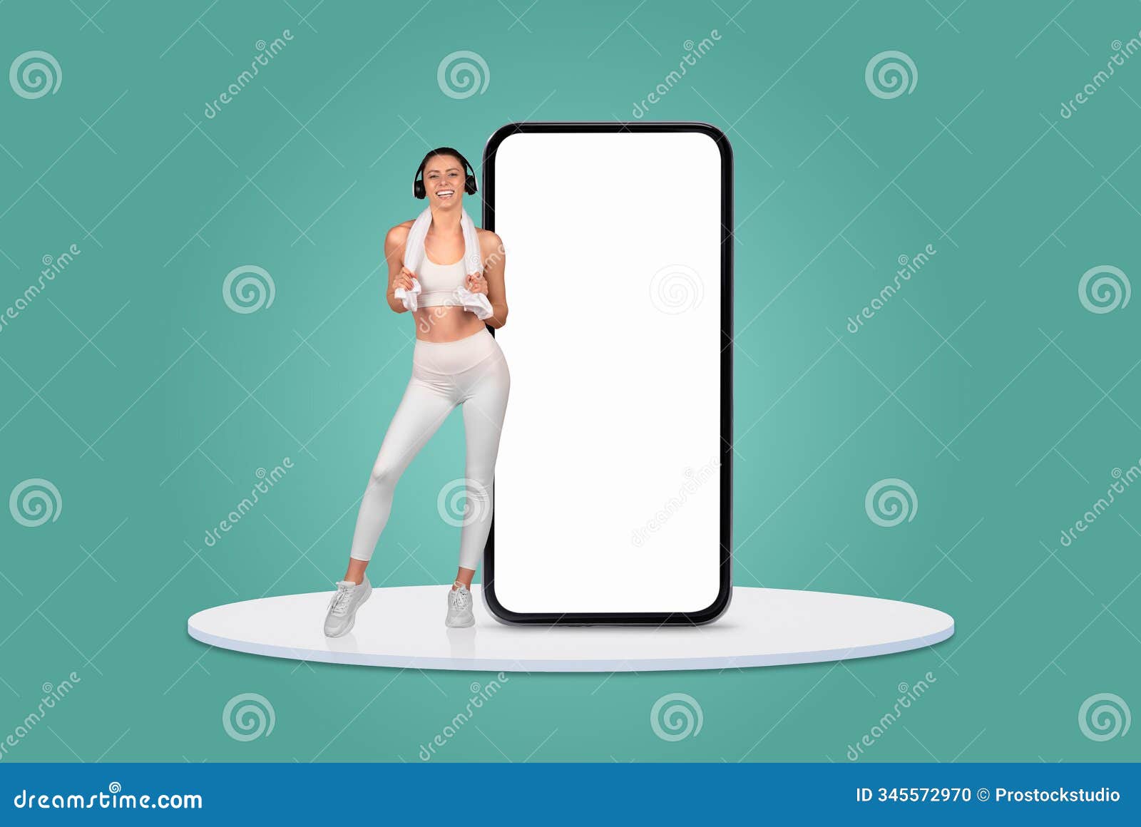 woman in activewear dances while holding a game controller next to a smartphone