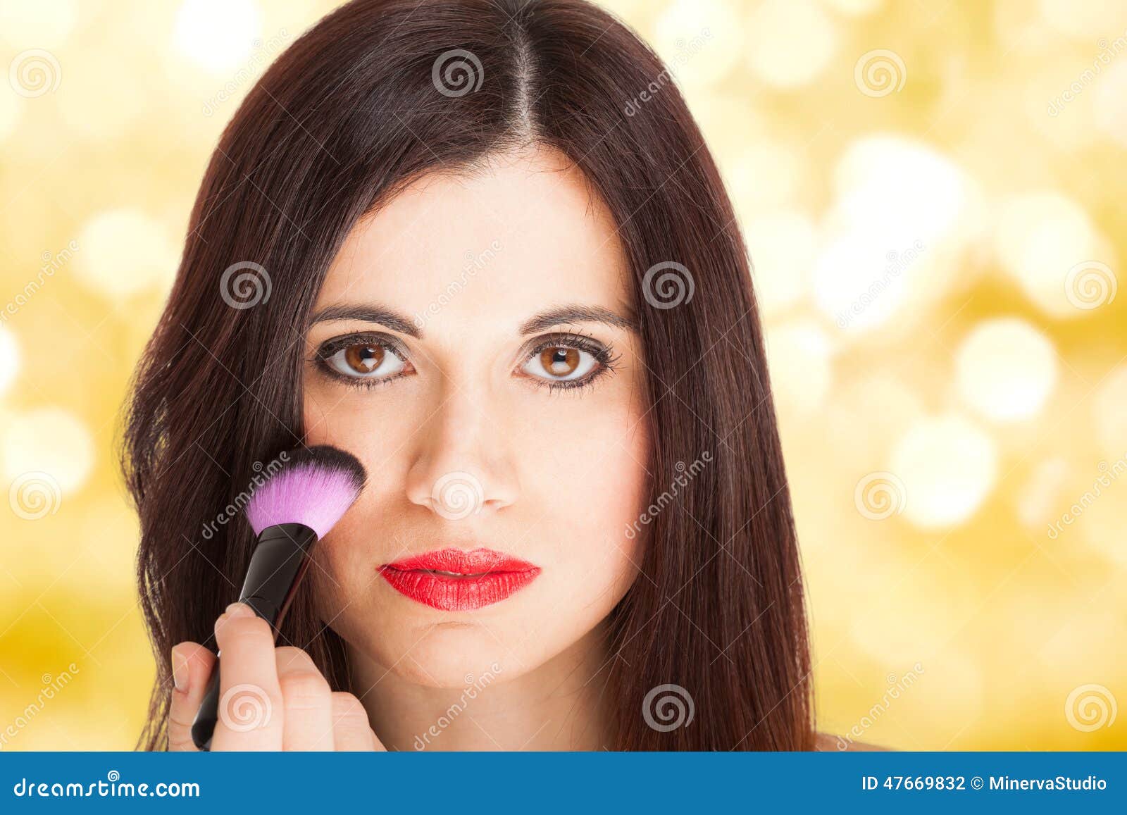 Portrait of a beautiful woman applying blusher on her face