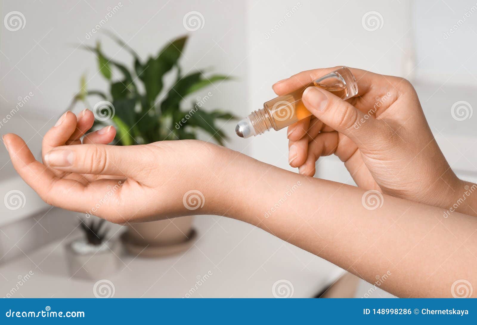 woman applying essential oil on wrist indoors