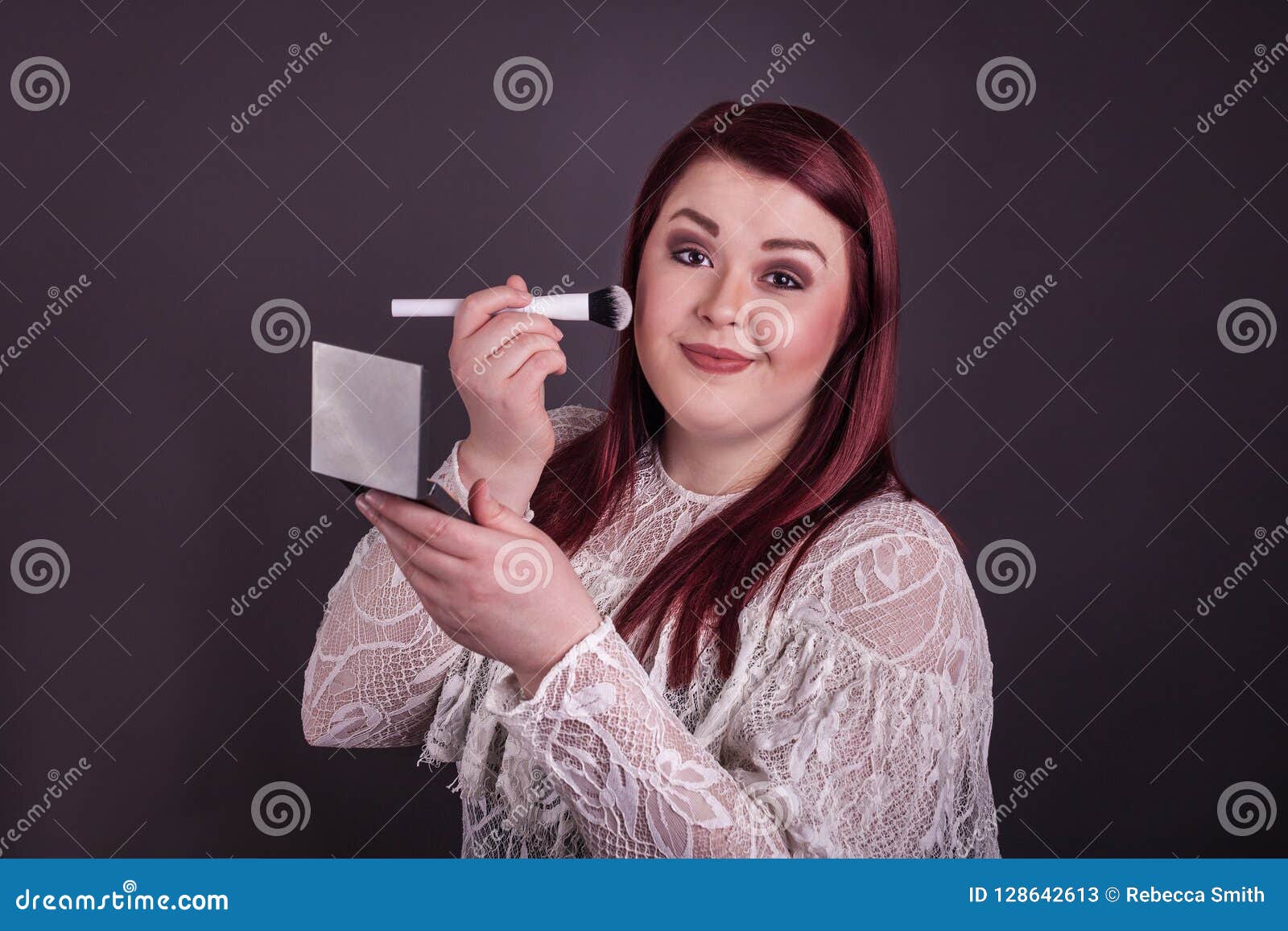 Woman Applying Makeup with Brush Holding Compact Mirror Stock Image