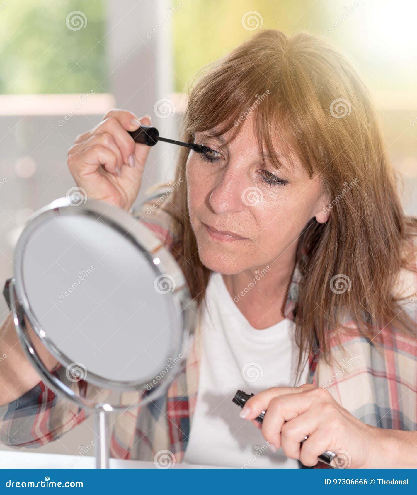 Woman Applying Mascara on Her Eyelashes, Light Effect Stock Photo
