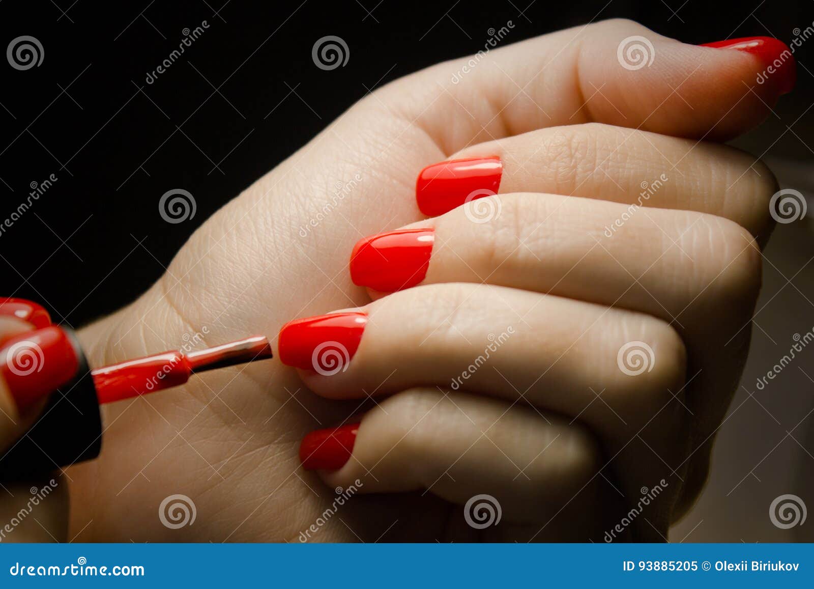 woman applying nail polish on her manicured nail carefully