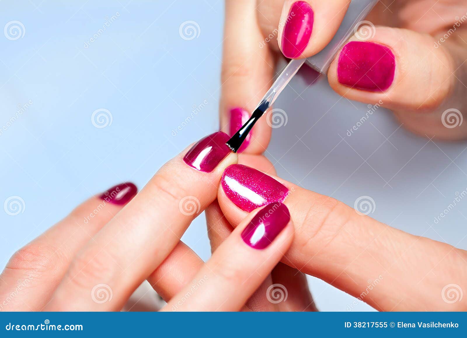woman applying nail varnish to finger nails