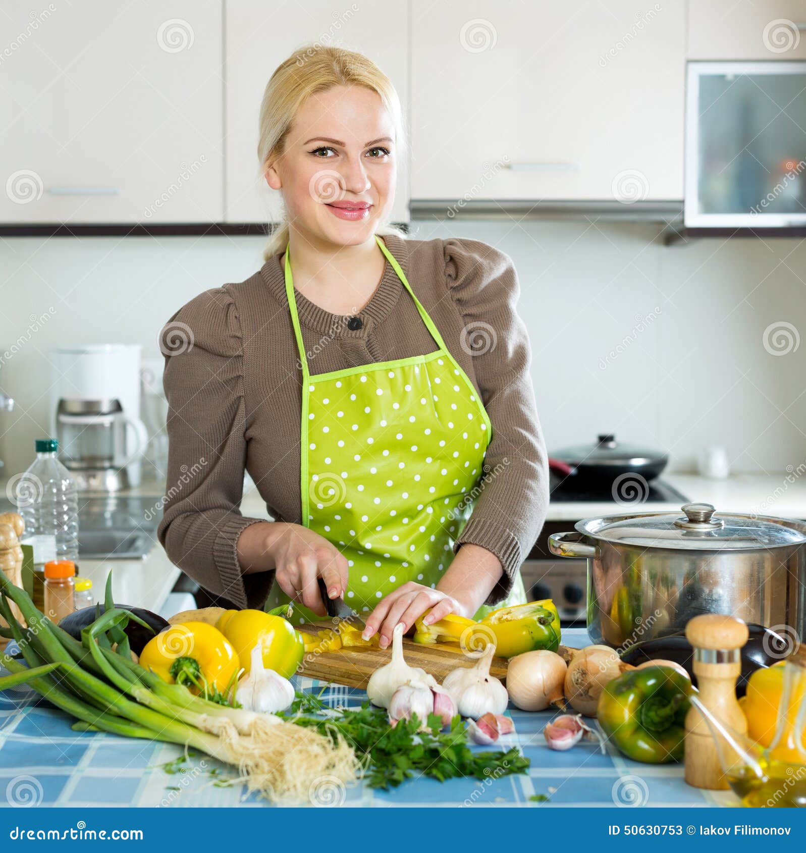 Young woman in an apron in her kitchen taking food out of 