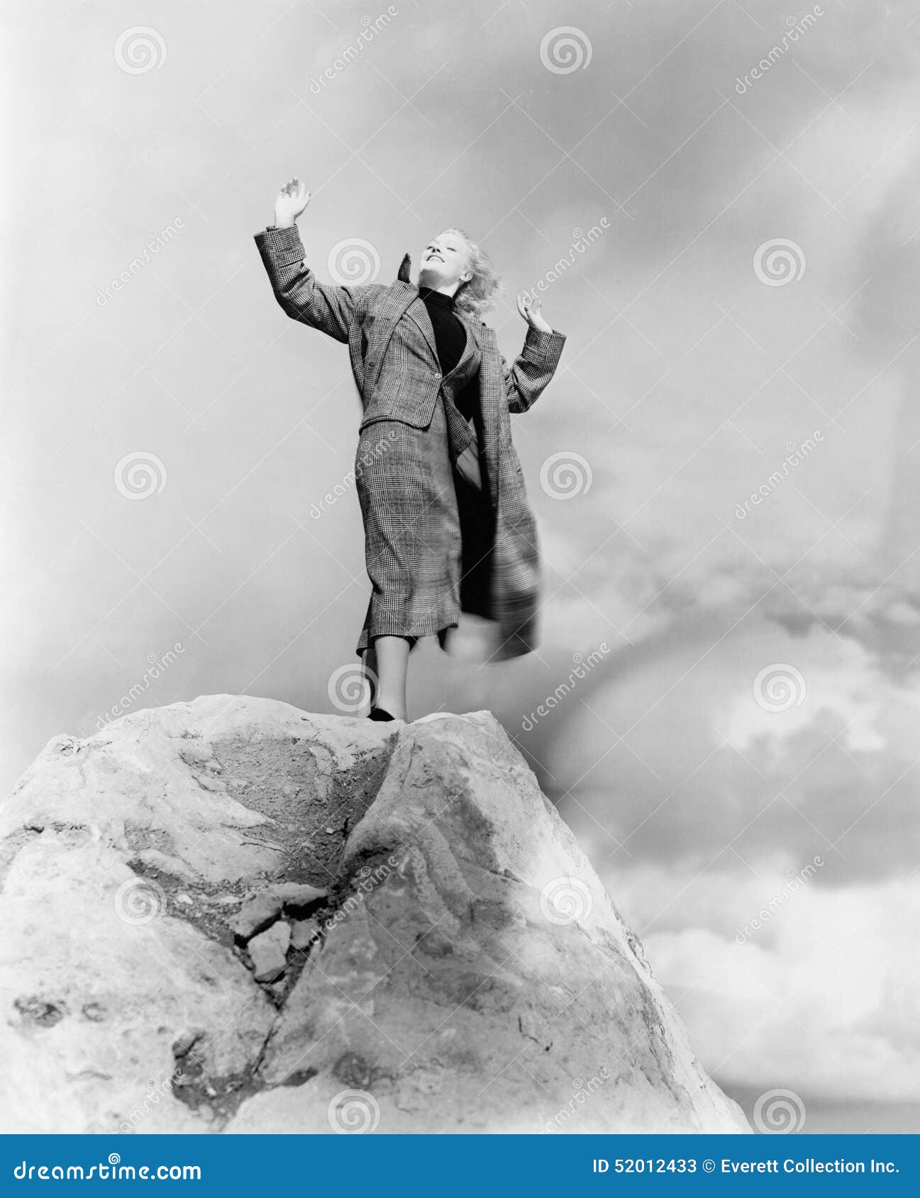 woman atop rock on windy day