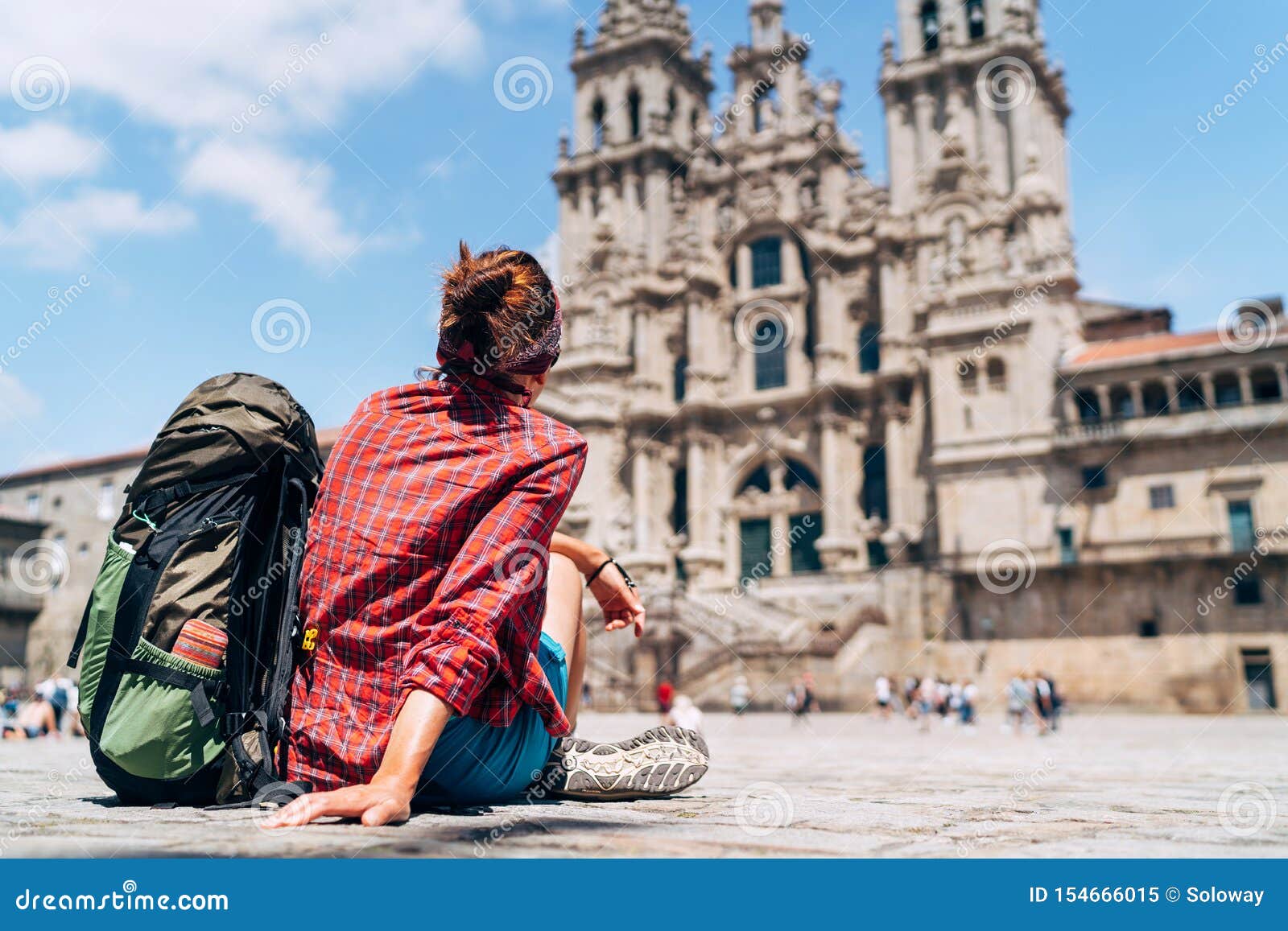 woman backpacker piligrim siting on the obradeiro square plaza in santiago de compostela