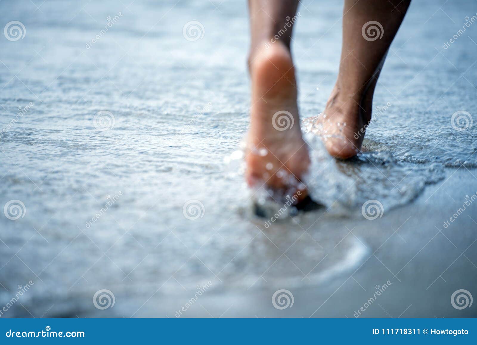 toe woman bare foot walking on the summer beach. close up leg of young woman walking along wave of sea water and sand on the beach