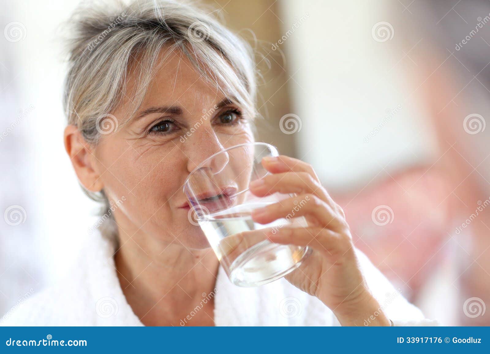 woman in bathrobe drinking water