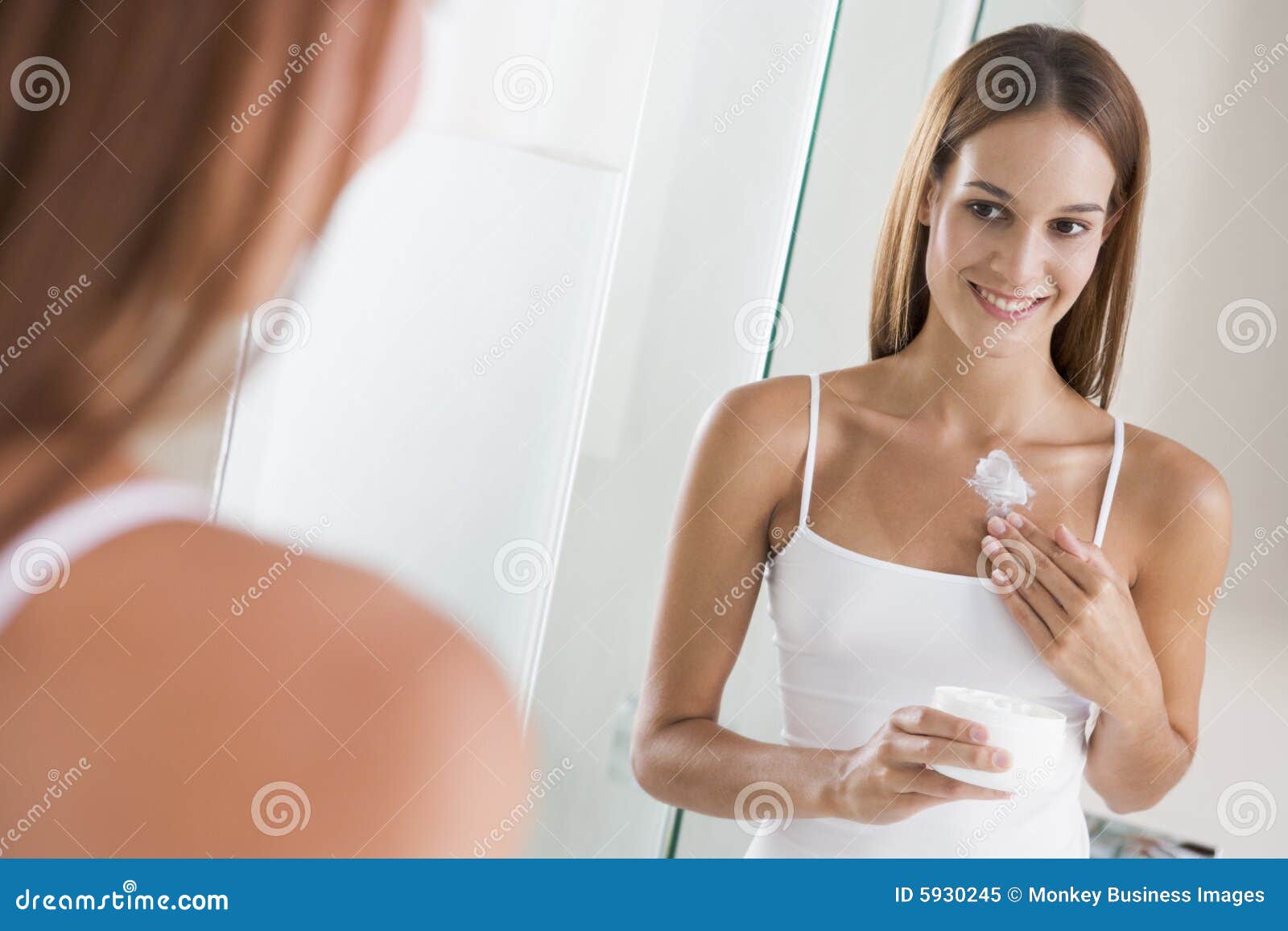 woman in bathroom applying lotion