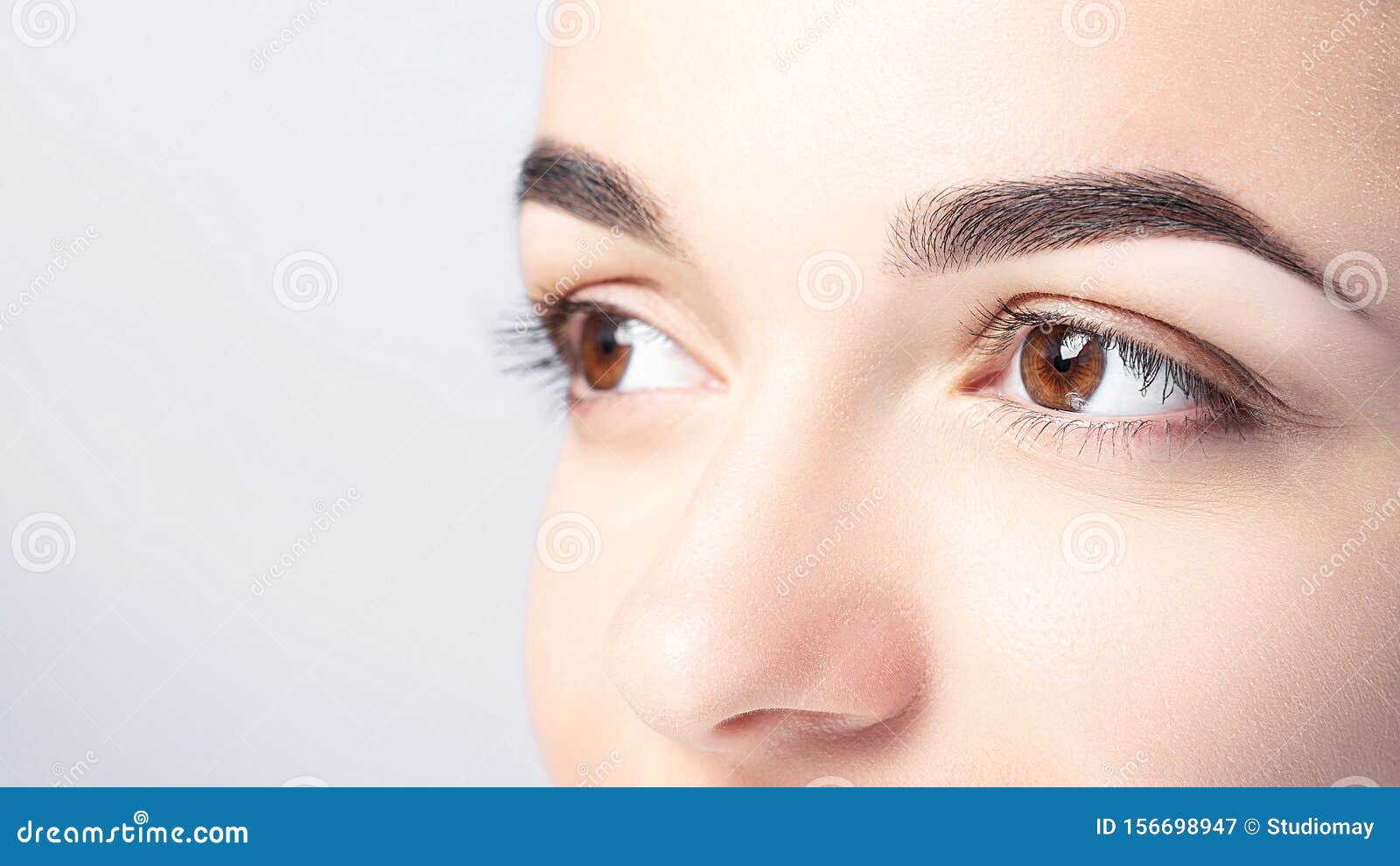 woman with beautiful eyebrows close-up on a light background with copy space. microblading, microshading, eyebrow tattoo, henna,