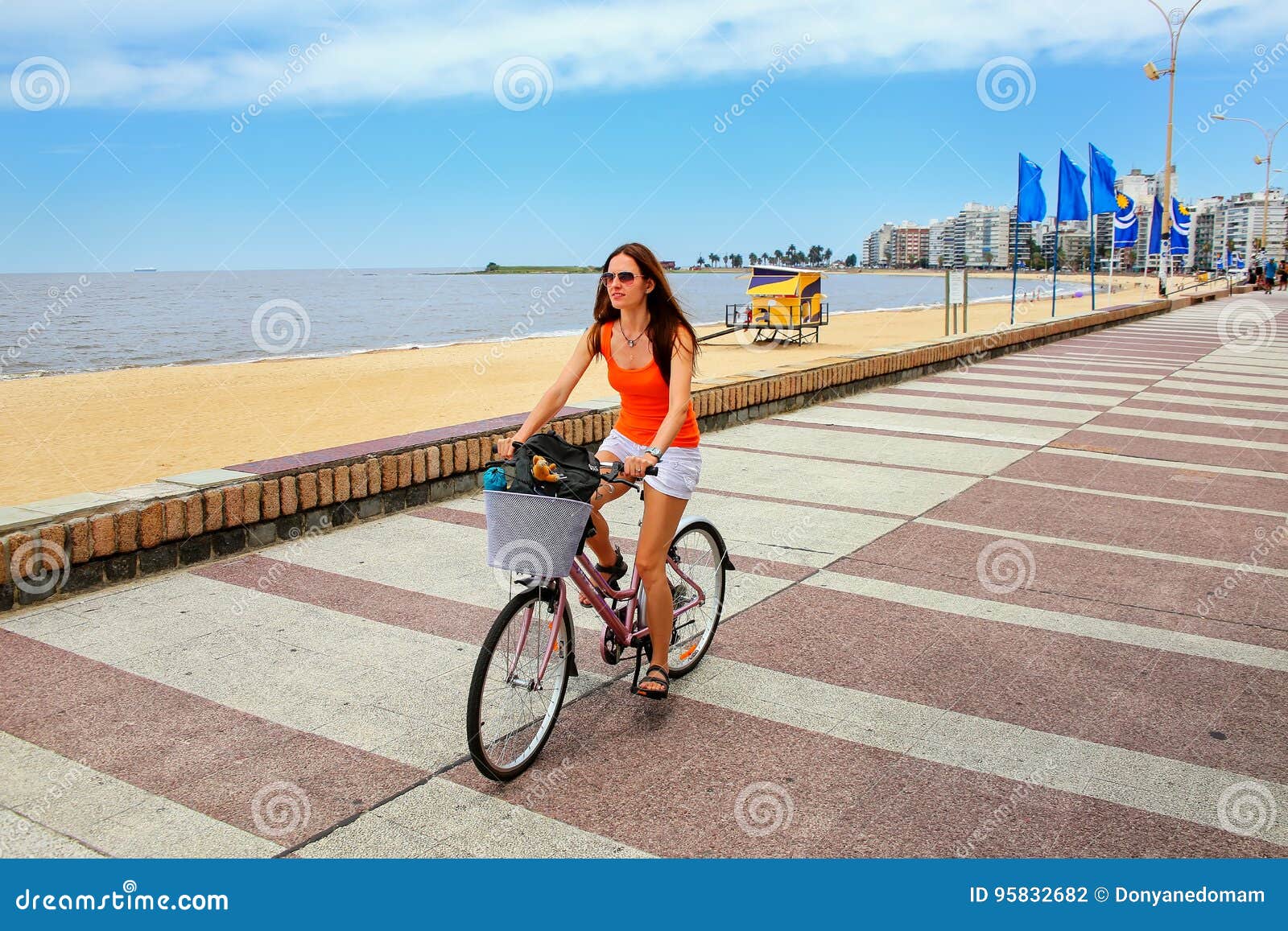 woman biking on the boulevard along pocitos beach in montevideo, uruguay.