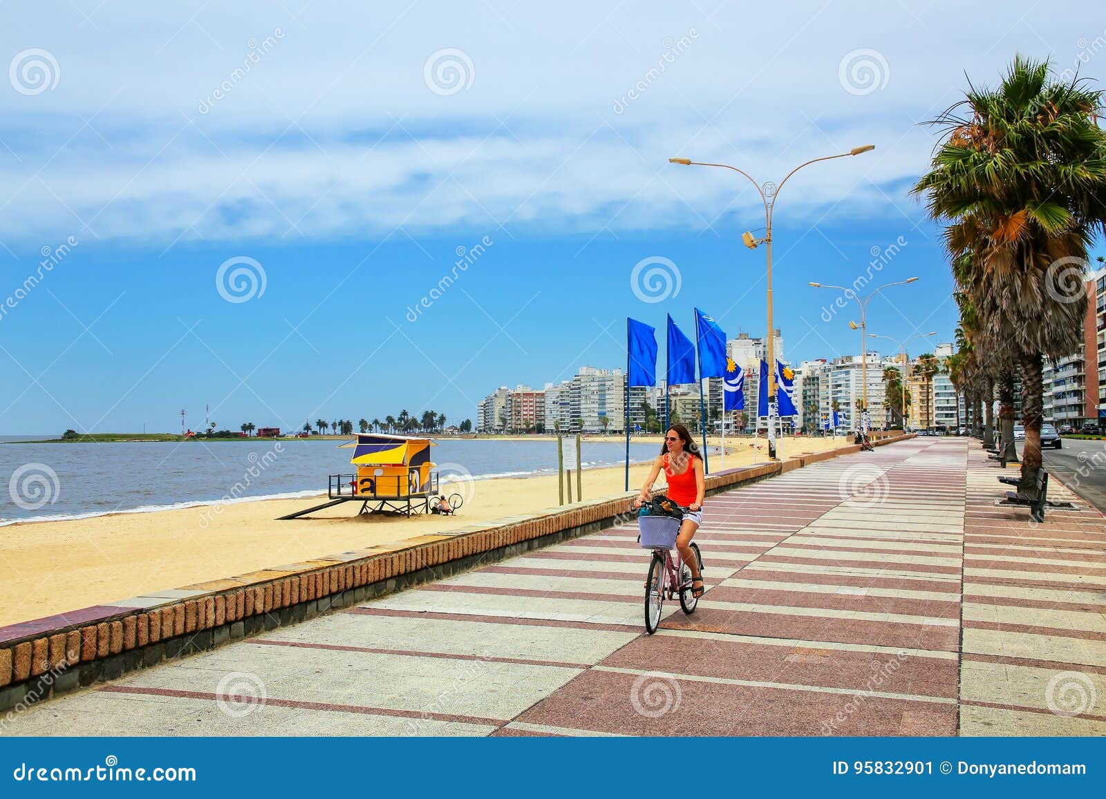 woman biking on the boulevard along pocitos beach in montevideo,