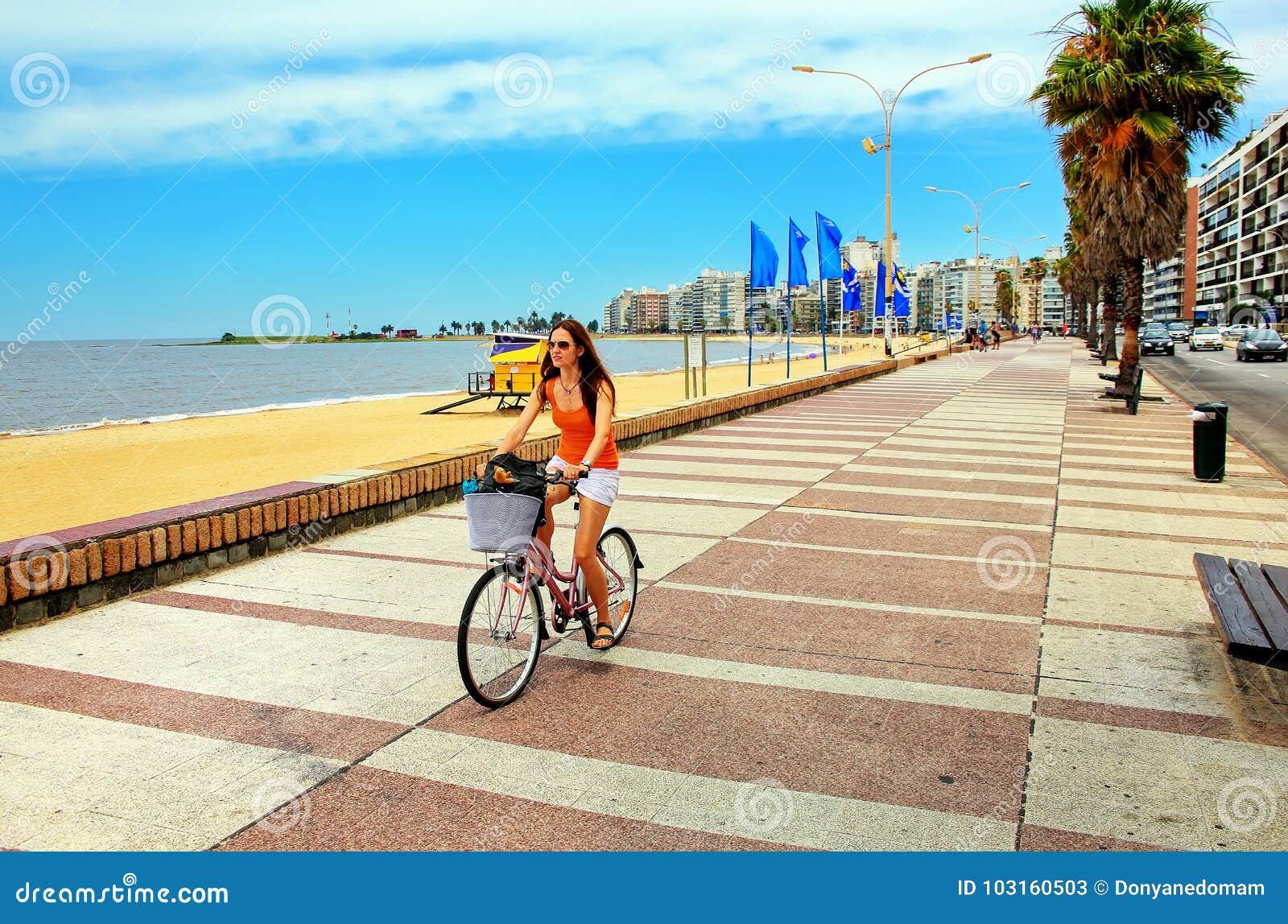 woman biking on the boulevard along pocitos beach in montevideo, uruguay.
