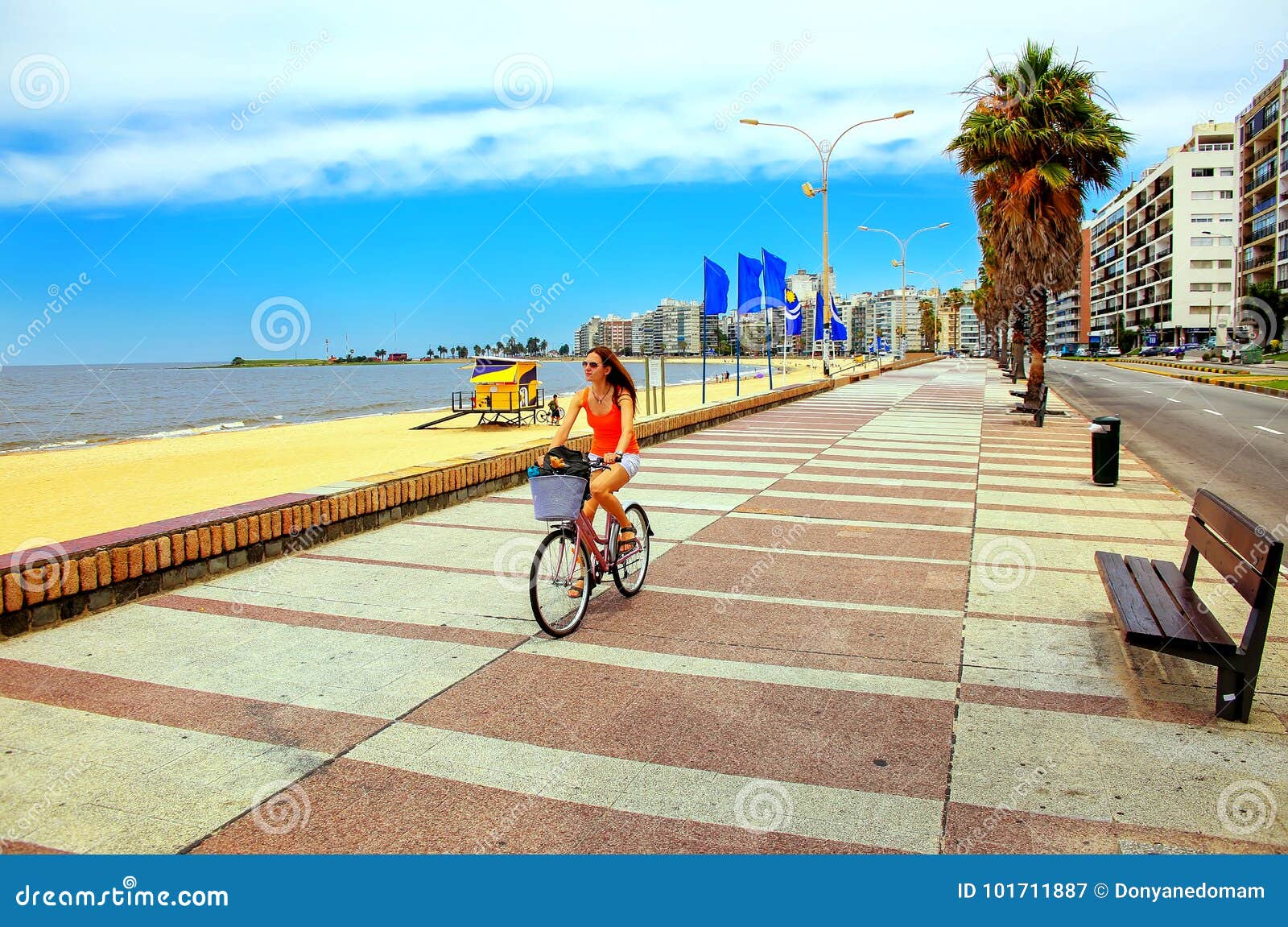 woman biking on the boulevard along pocitos beach in montevideo, uruguay.