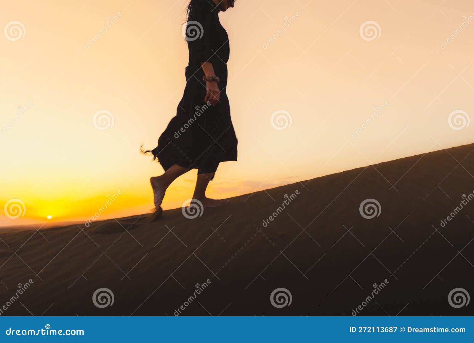 woman black dress walking in the dubai desert sand dunes with footsteps in the sand during sunset, woman walk golden sand summer