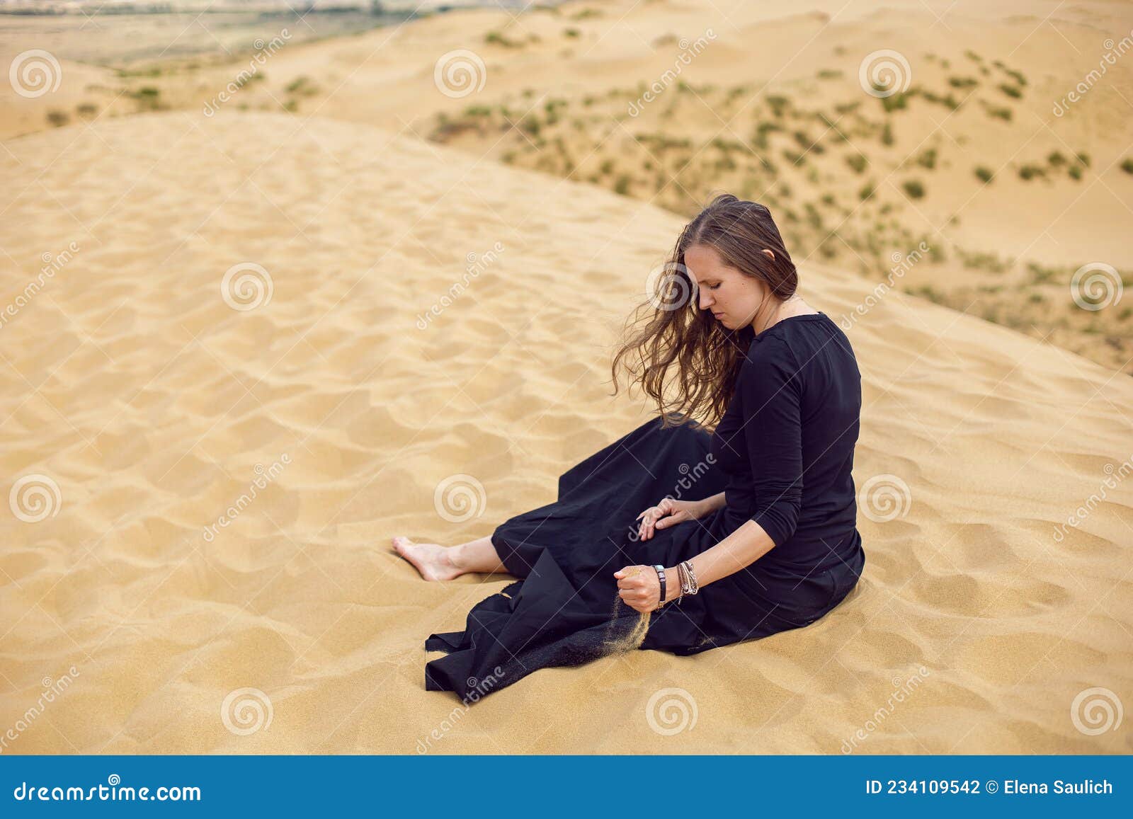 Woman In Black Long Dress Sit Through The Desert Dunes In Summer