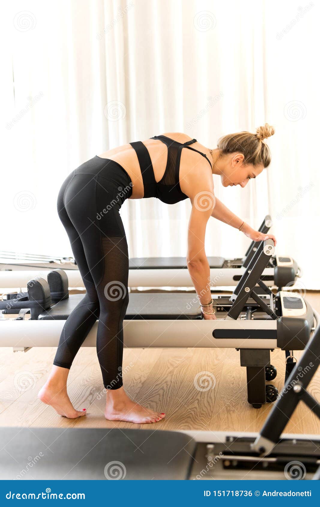 Woman in Workout Clothes Adjusting Reformer Pilates Bed Stock