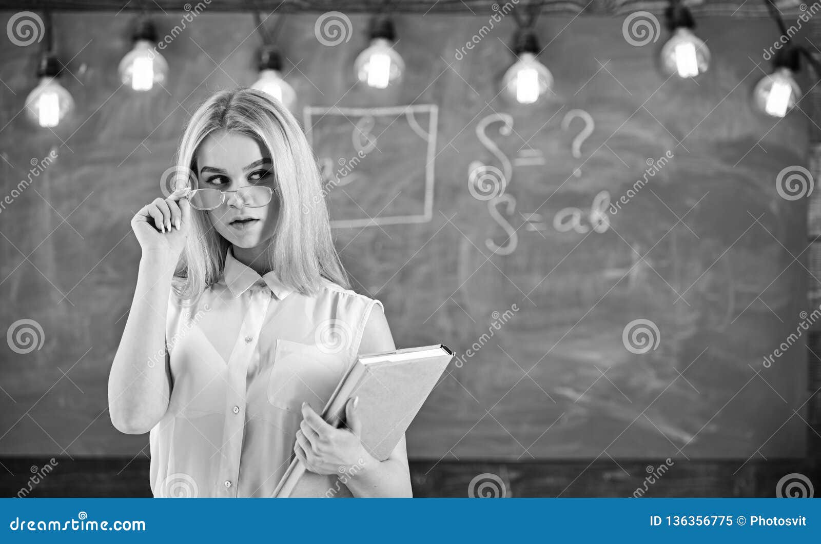 Woman With Book Starts Lesson Gazes At Audience While Taking Off Eyeglasses Teacher Looks