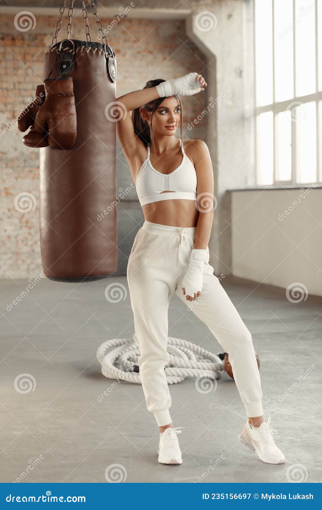 Strong woman punching boxing bag during training with trainer  Free Stock  Photo