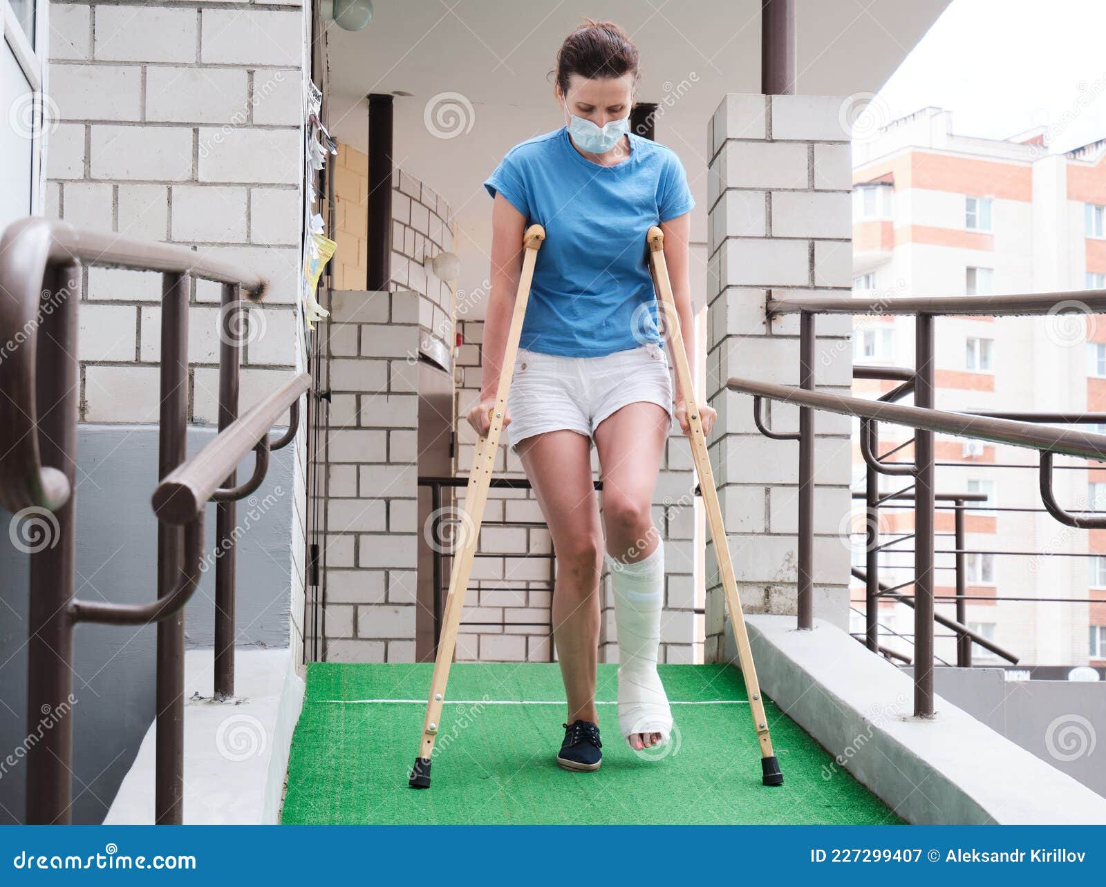 A Woman With A Broken Leg Walks Down A Ramp Using Orthopedic Crutches A Woman With A Broken Leg Walks Down A Ramp Using Orthopedic Crutches