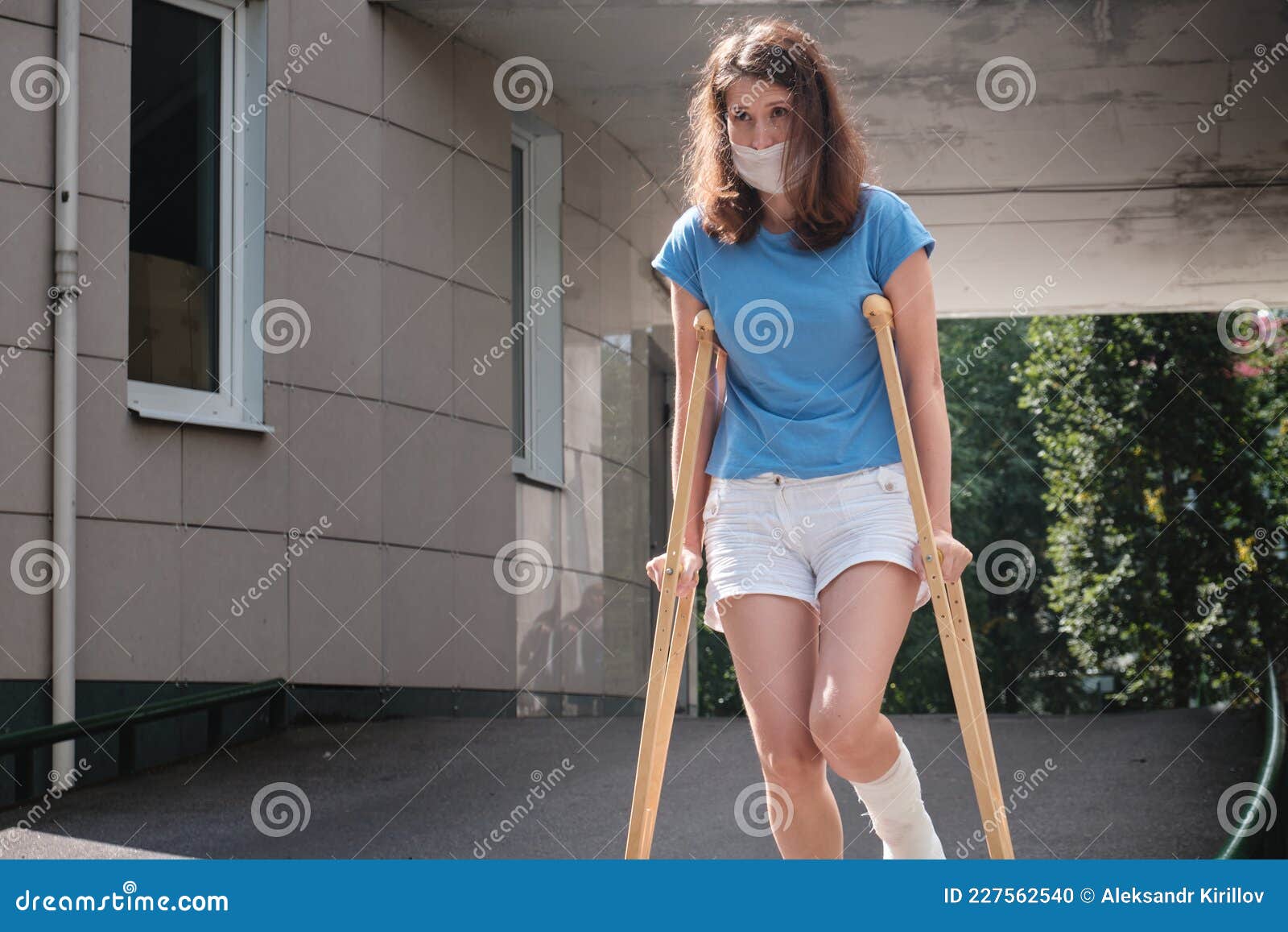 A Woman With A Broken Leg Walks Down A Ramp Using Orthopedic Crutches A Woman With A Broken Leg Walks Down A Ramp Using Orthopedic Crutches
