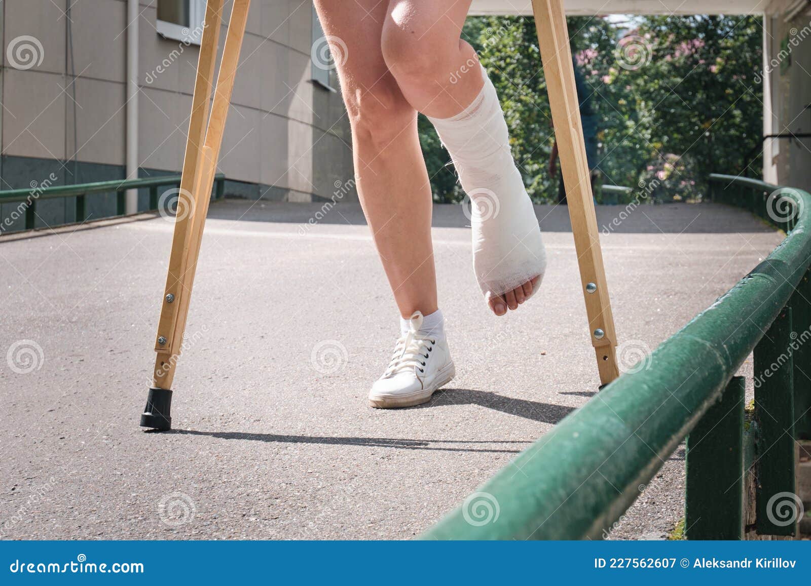 A Woman With A Broken Leg Walks Down A Ramp Using Orthopedic Crutches A Woman With A Broken Leg Walks Down A Ramp Using Orthopedic Crutches
