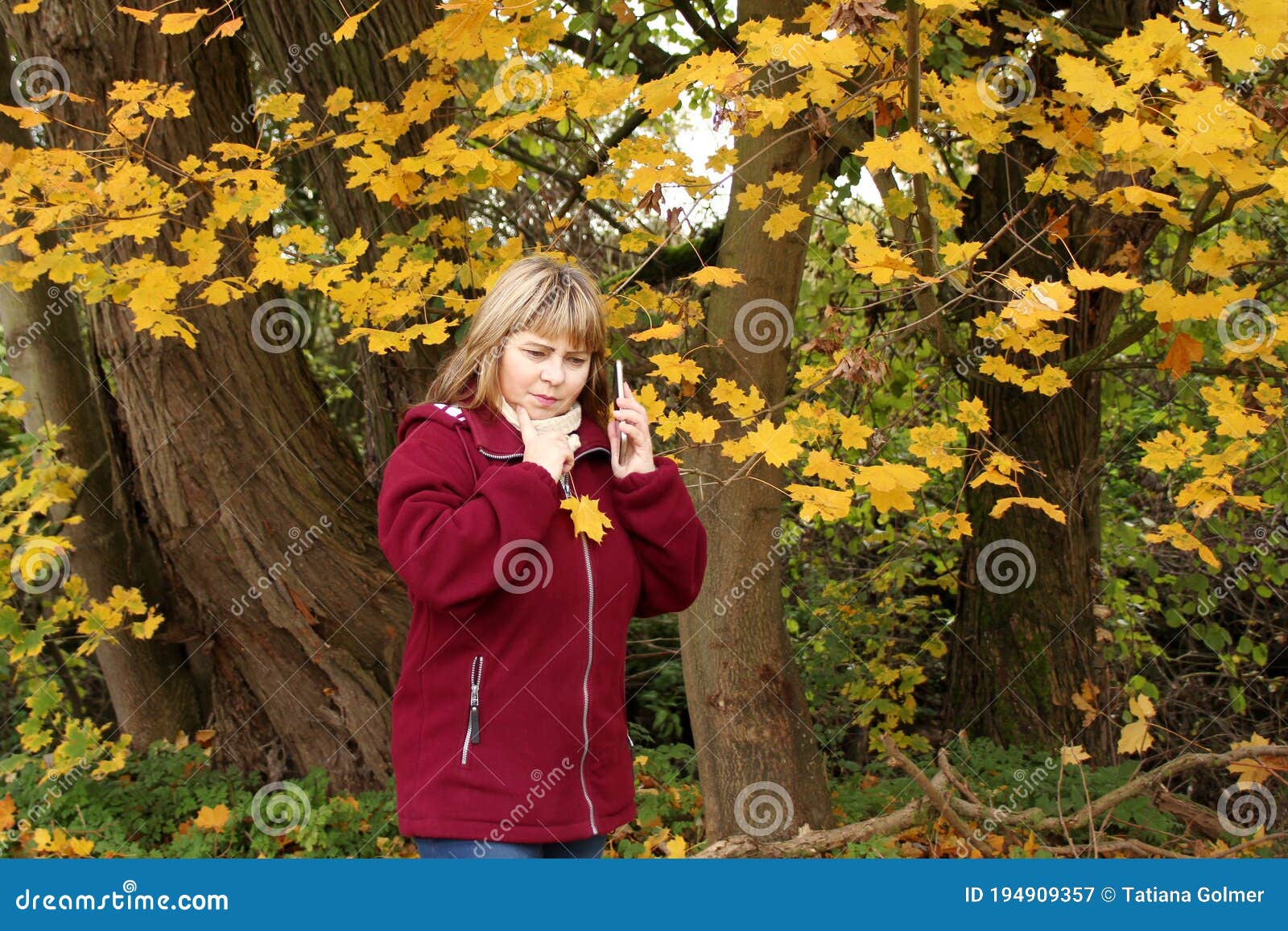 Woman in a Burgundy Fleece Jacket Talking on the Phone in an Autumn ...