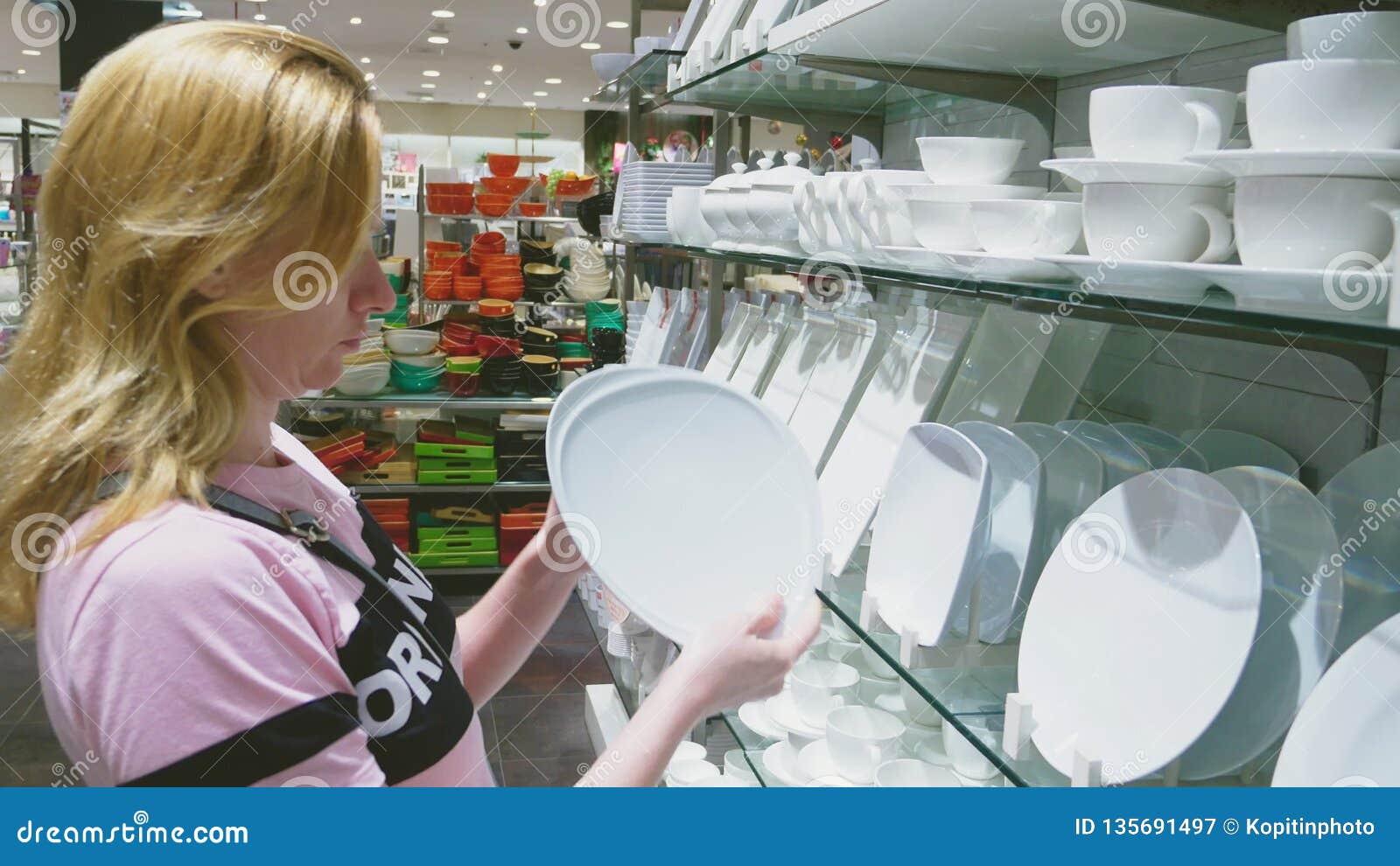 A Woman Buys Dishes in the Store, Examines Various Items of Dishes