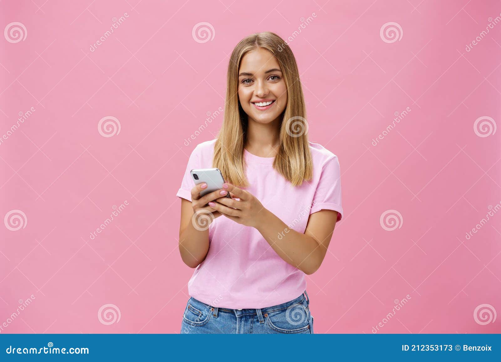 woman calling taxy via smartphone asking friend address smiling cheerfully at camera holding phone with both hands over