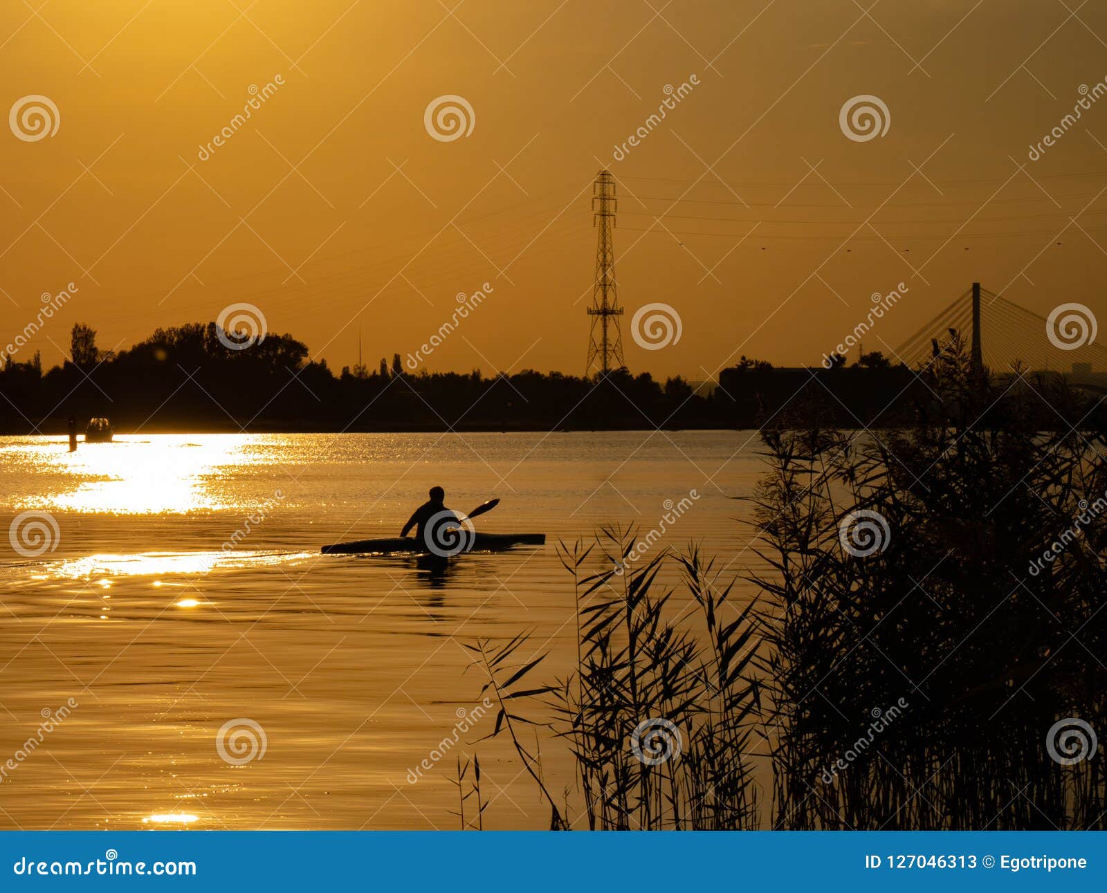 woman canoeing at sunset on vistula river, poland. amazing scenery and colors.