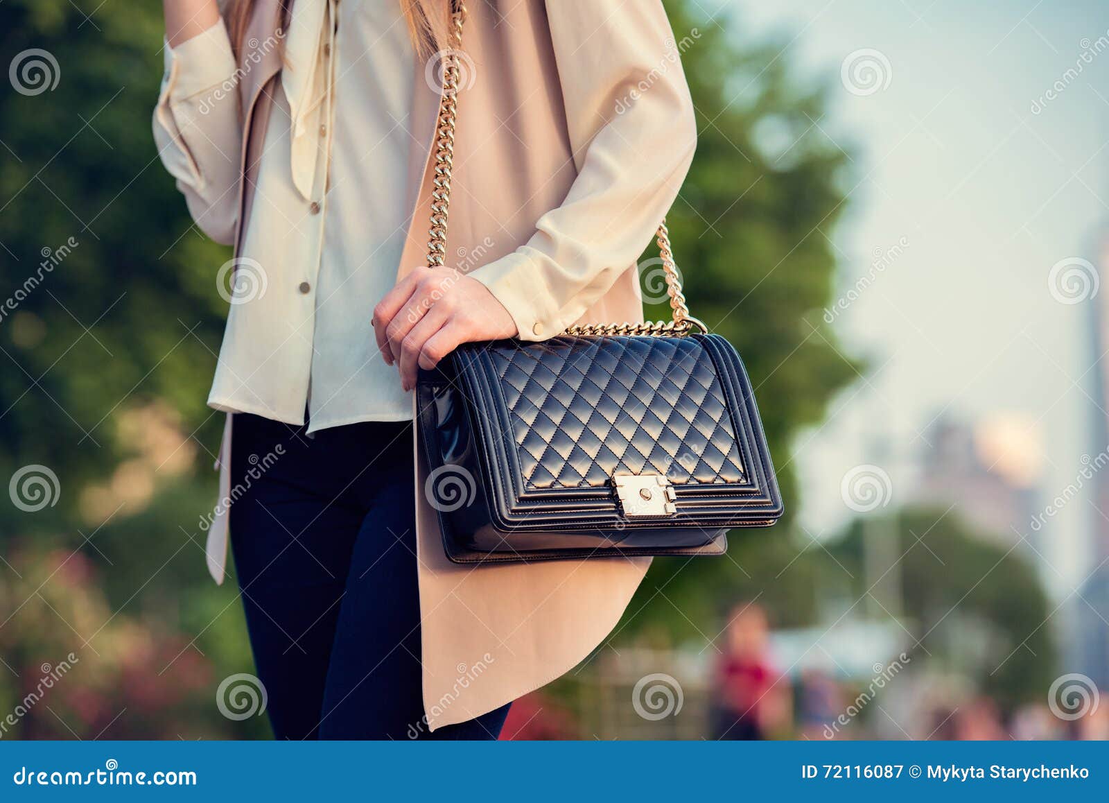 woman carrying elegant purses bag at city park