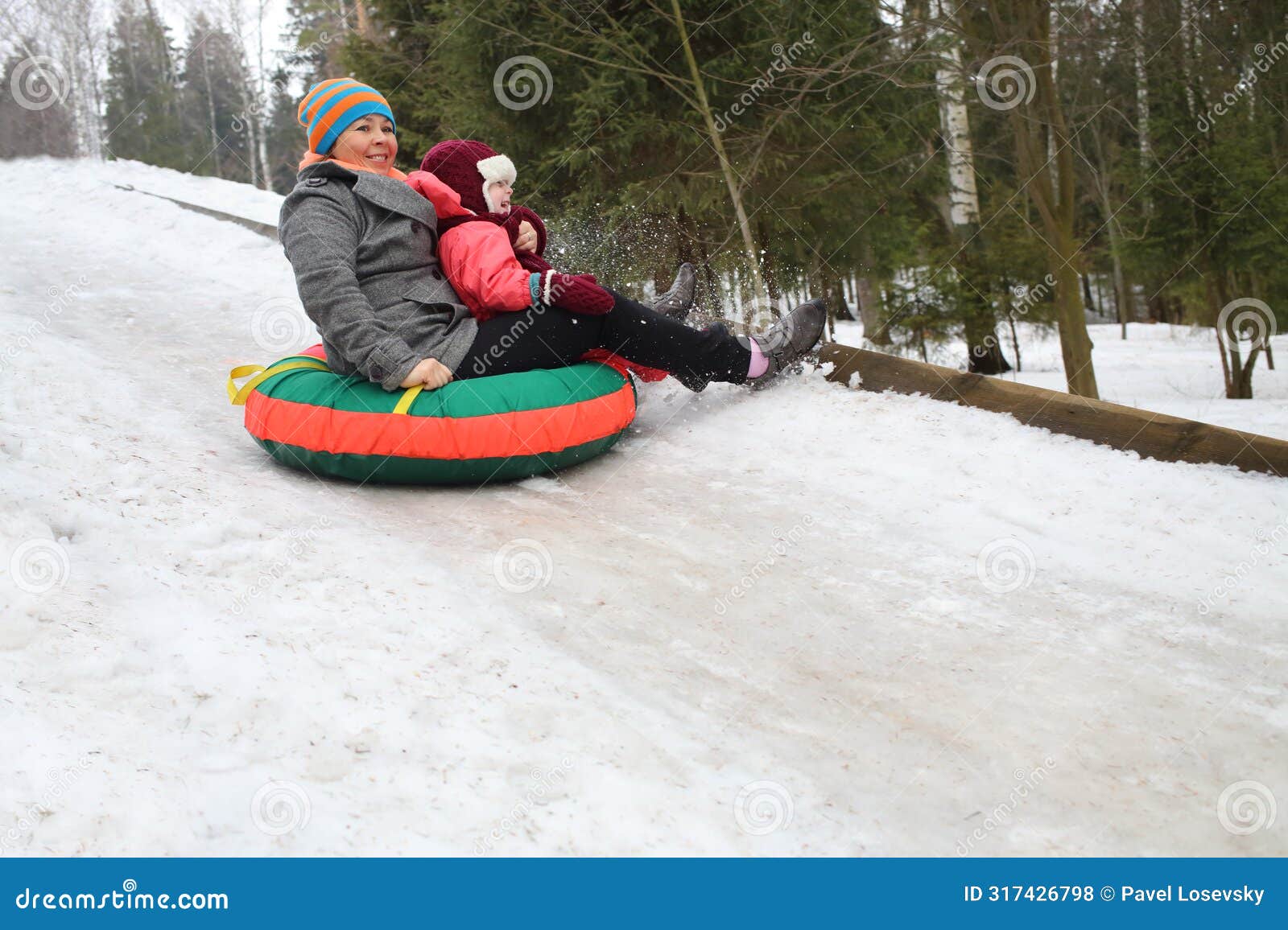woman with child rolling hills on a sledge in the