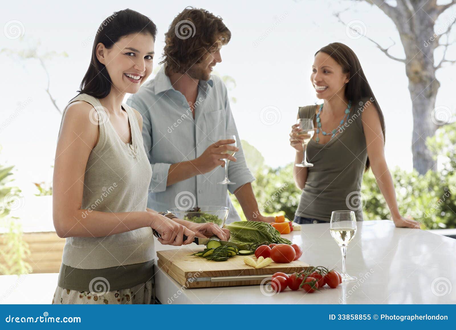woman chopping vegetables with friends communicating at kitchen counter