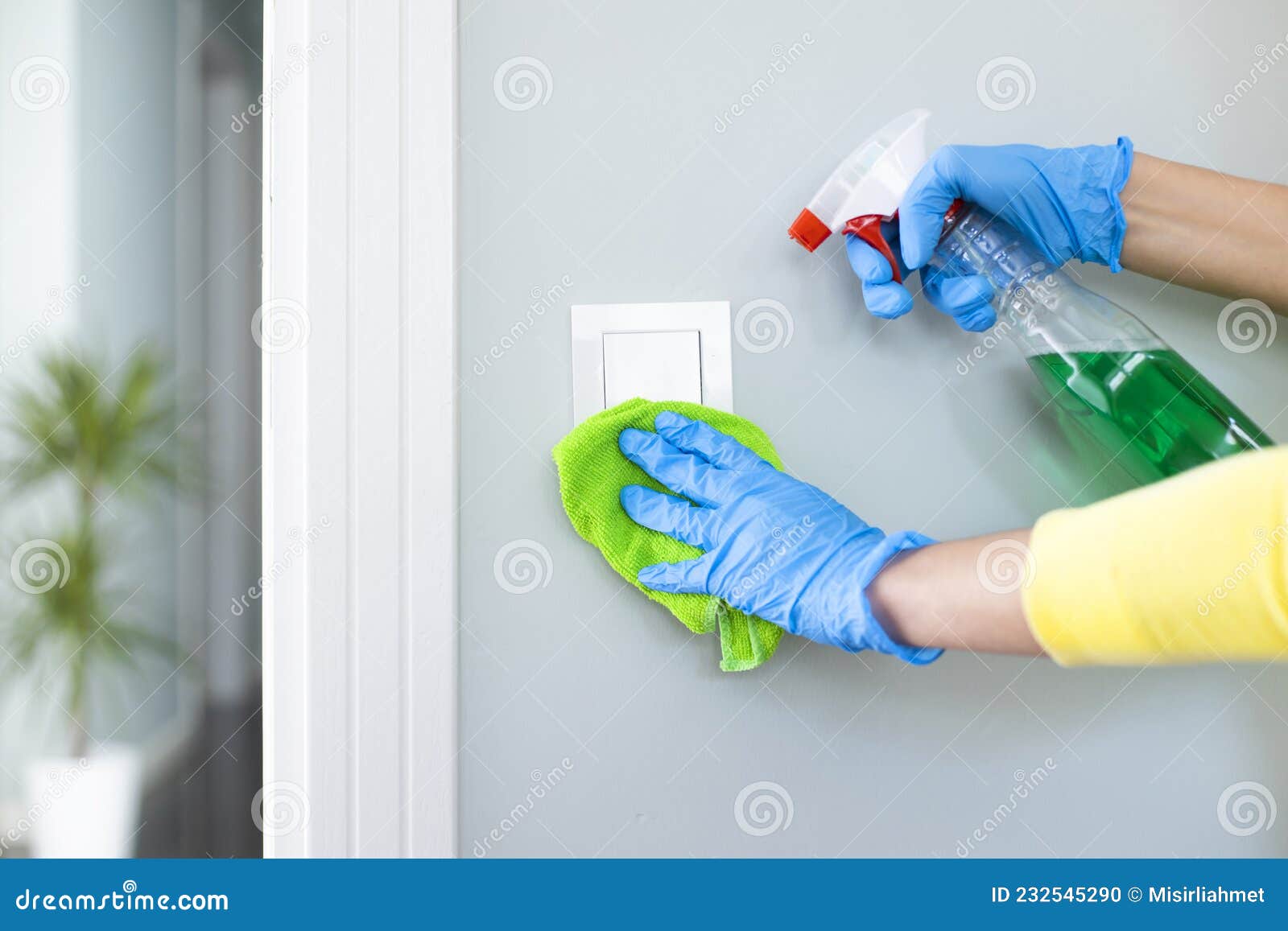 Woman Cleaning a Light Switch with a Disinfecting Spray Stock Photo