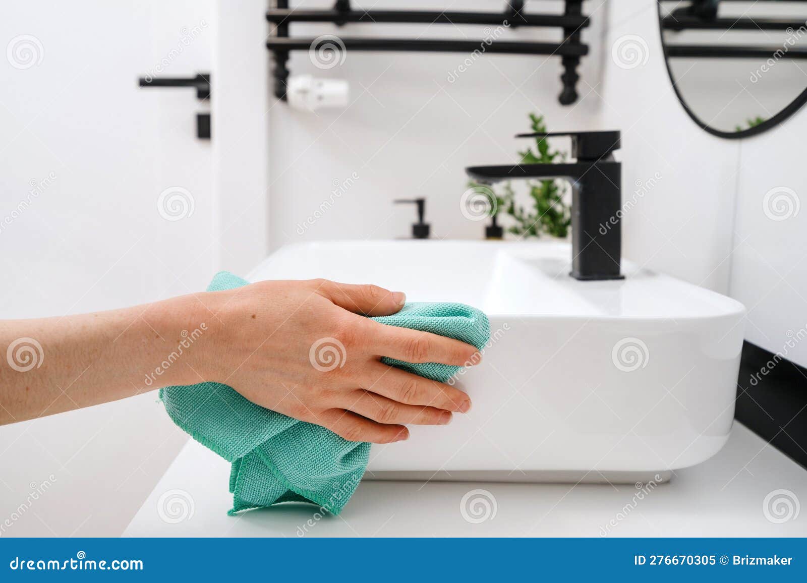 woman cleaning white washbasin with a cloth