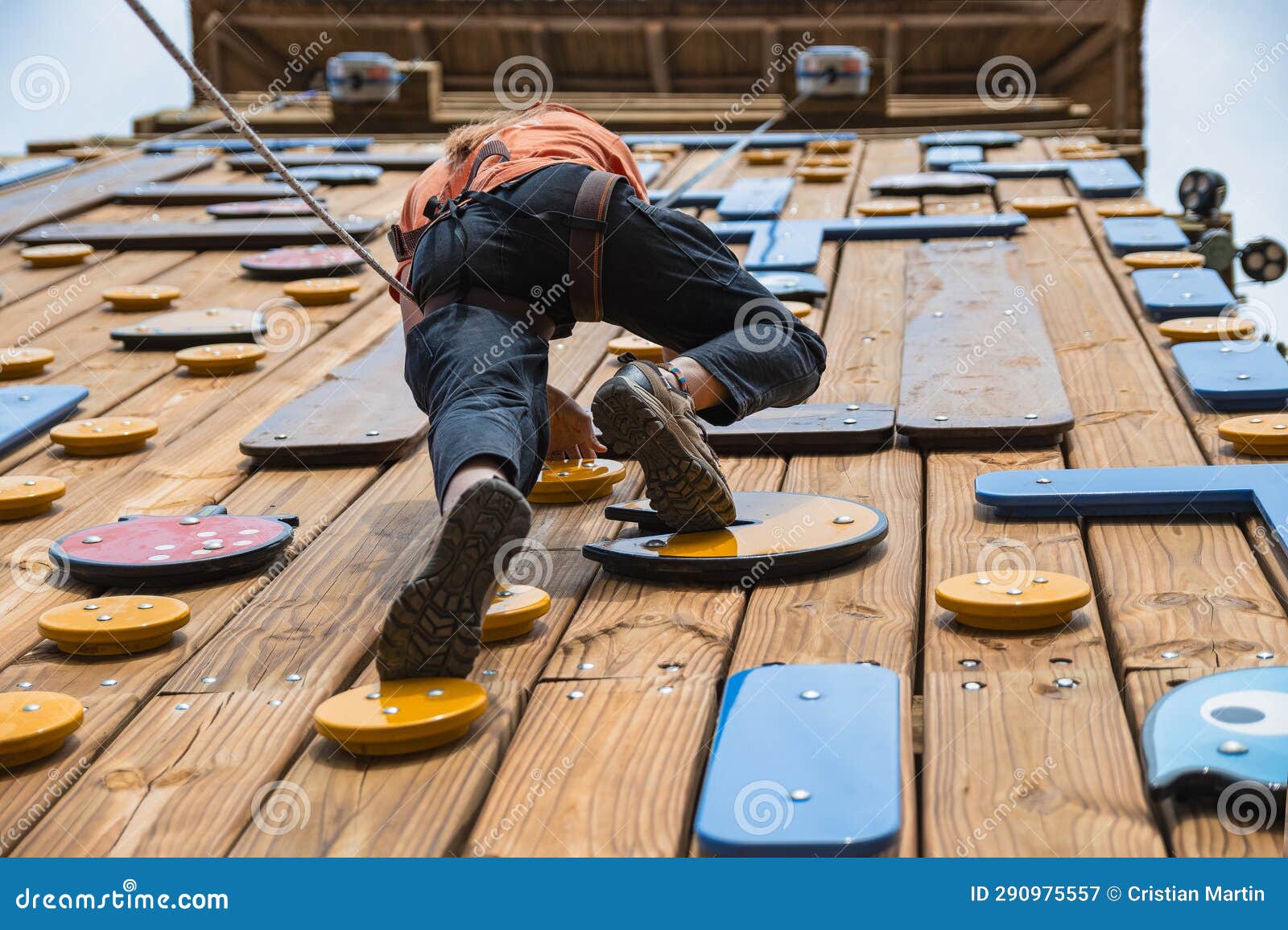 woman climbing wooden wall with rocks (palestra)