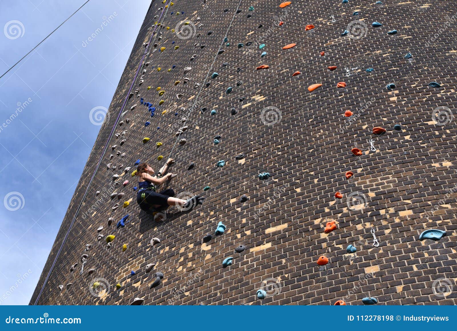 Woman Climbs Up an Artificial Rock Wall - Secured with a Rope Ag Stock ...