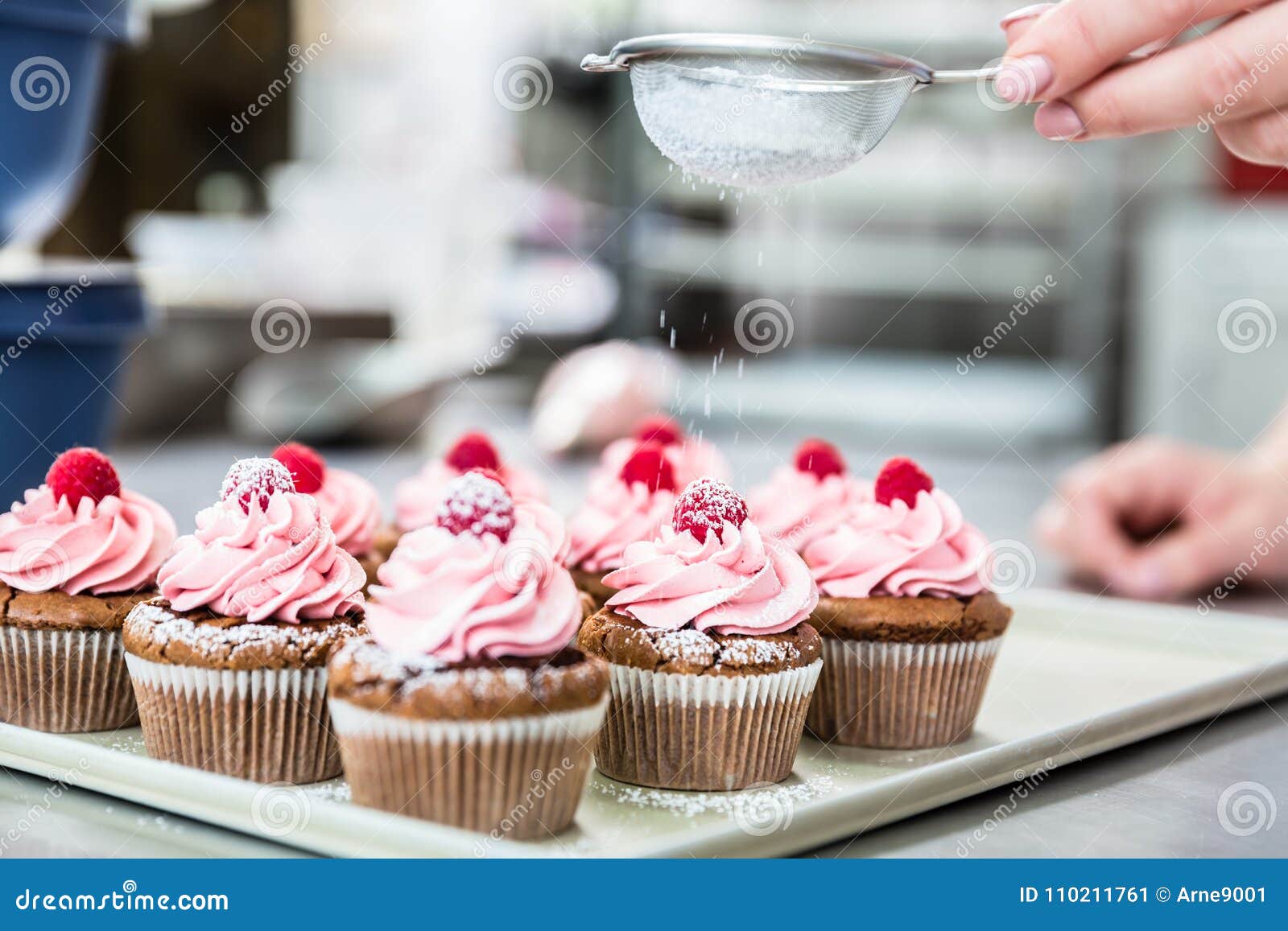 woman in confectionary icing cupcakes with sugar