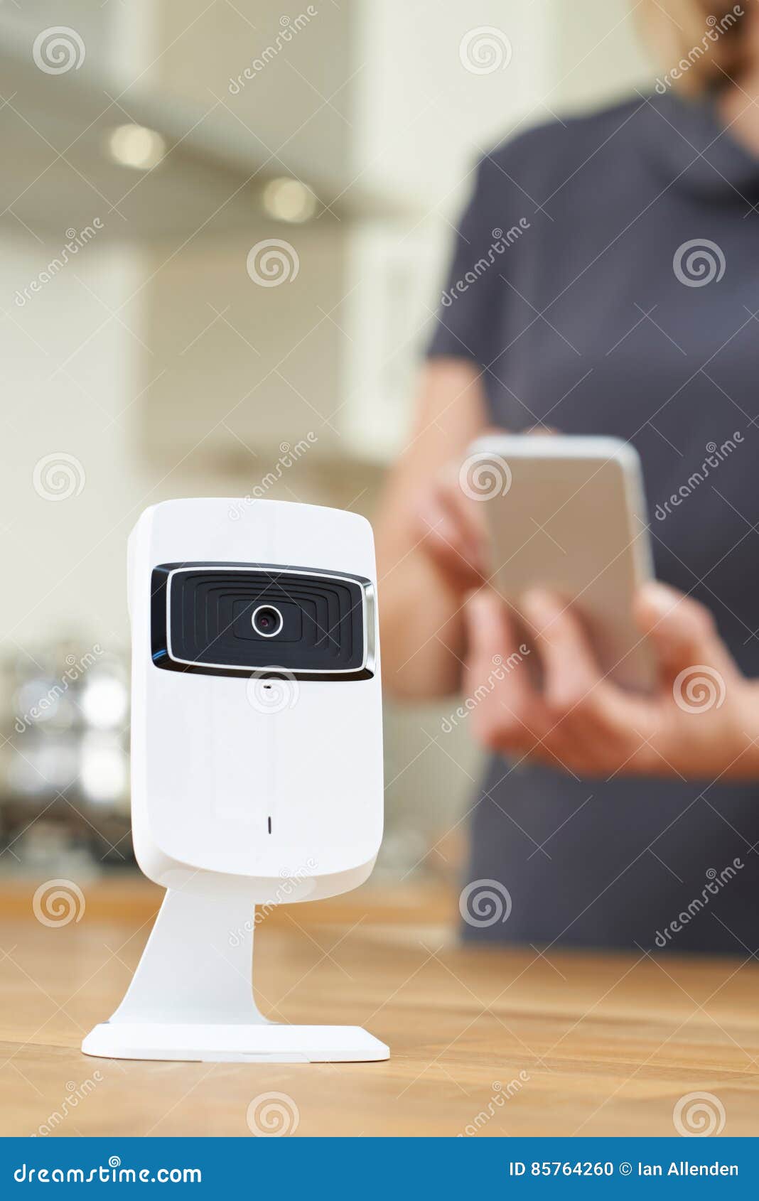 Woman Controlling Smart Security Camera Using App on Mobile Phone Stock