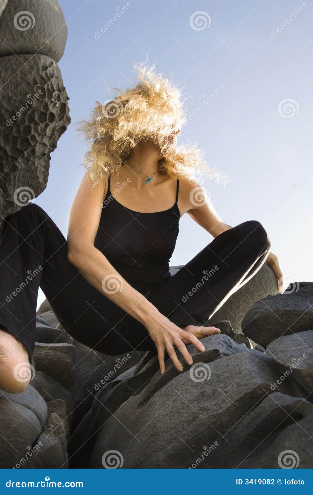 woman crouching on rocks.