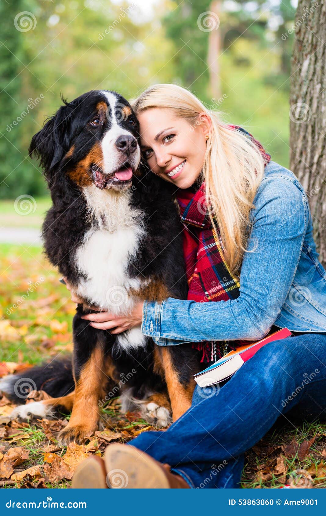 woman cuddling with dog outside in park