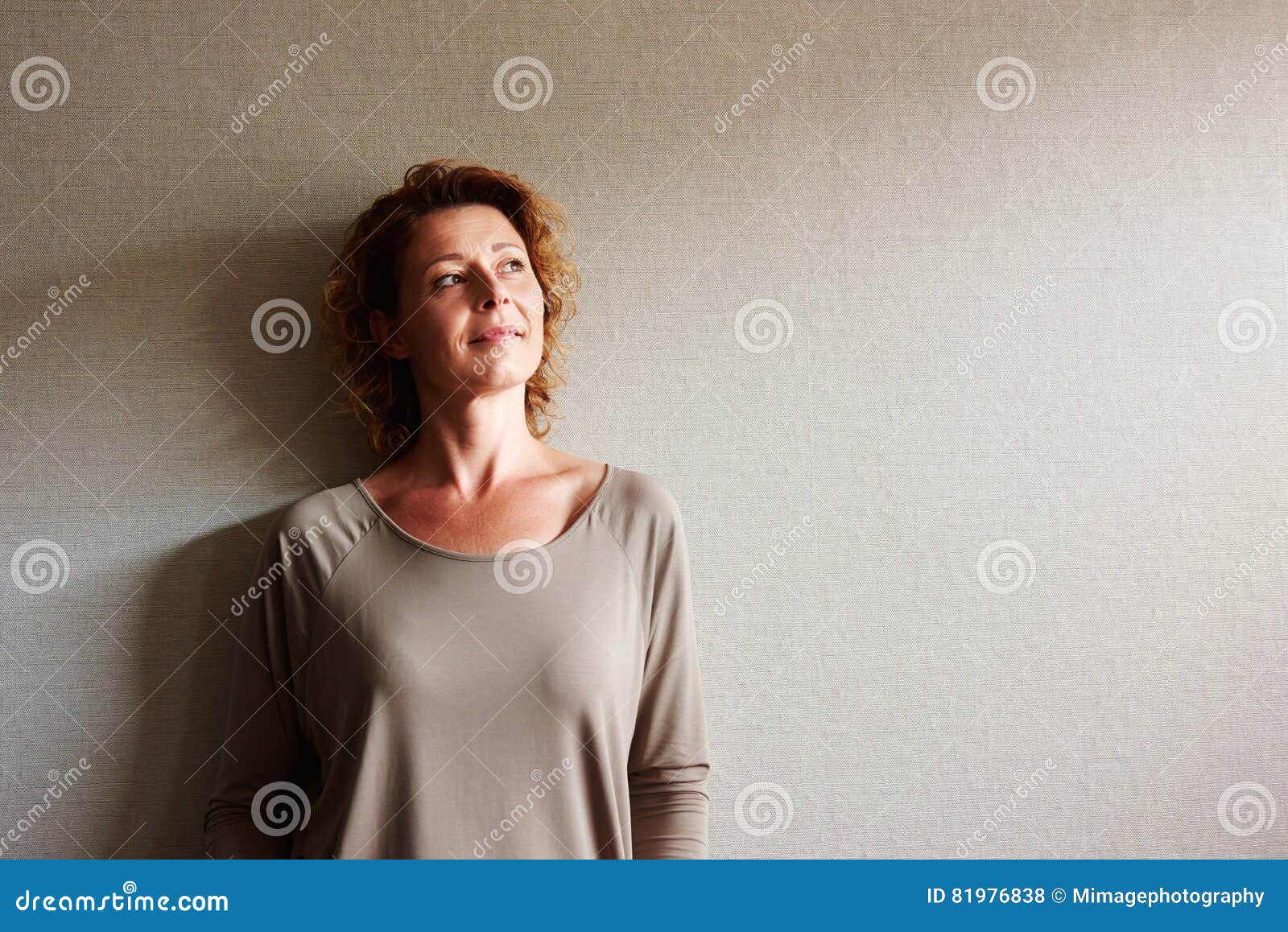 woman with curly hair leaning on wall in contemplation