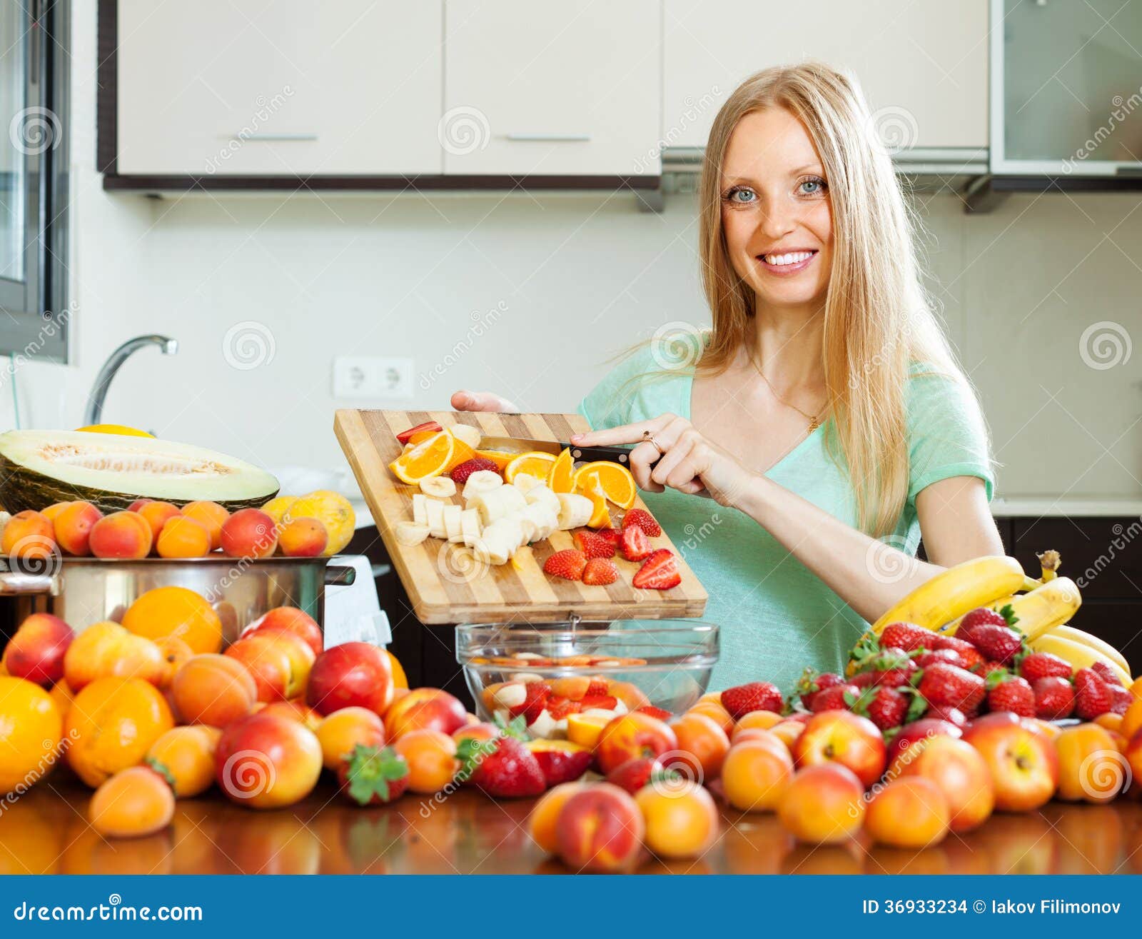 Blonde woman cutting fruits for salad at home